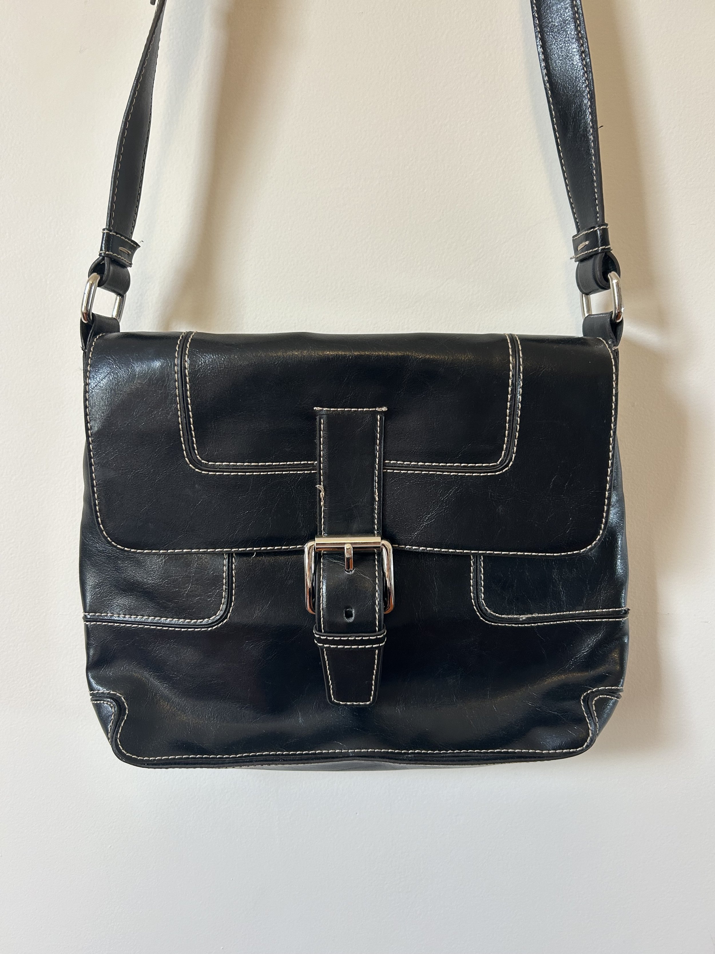 A close up shot of a second hand black bag with contrast stitching and silver hardware