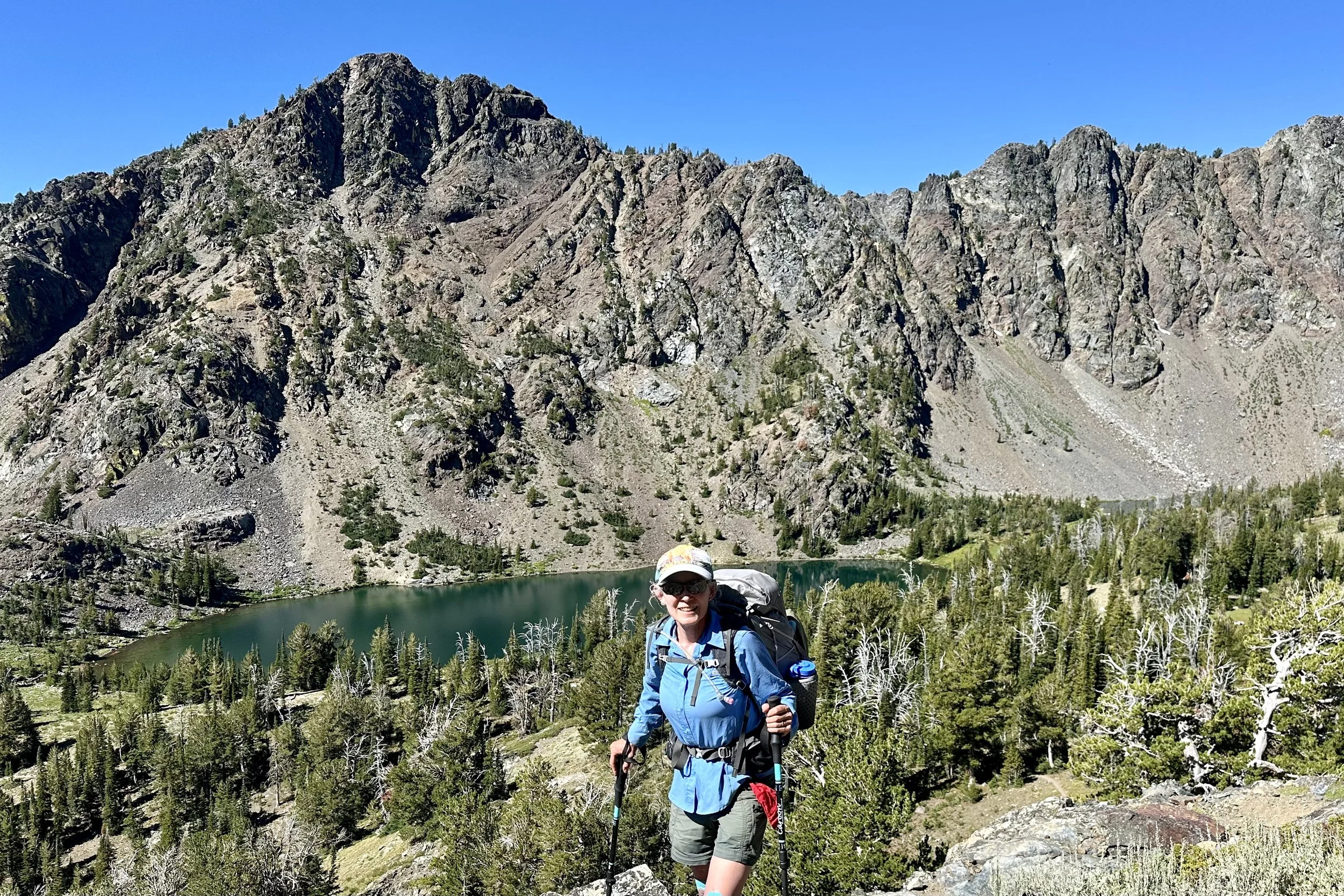 Midlife woman backpacking in the mountains near an alpine lake, reflecting strength, resilience, and vitality through movement in nature.