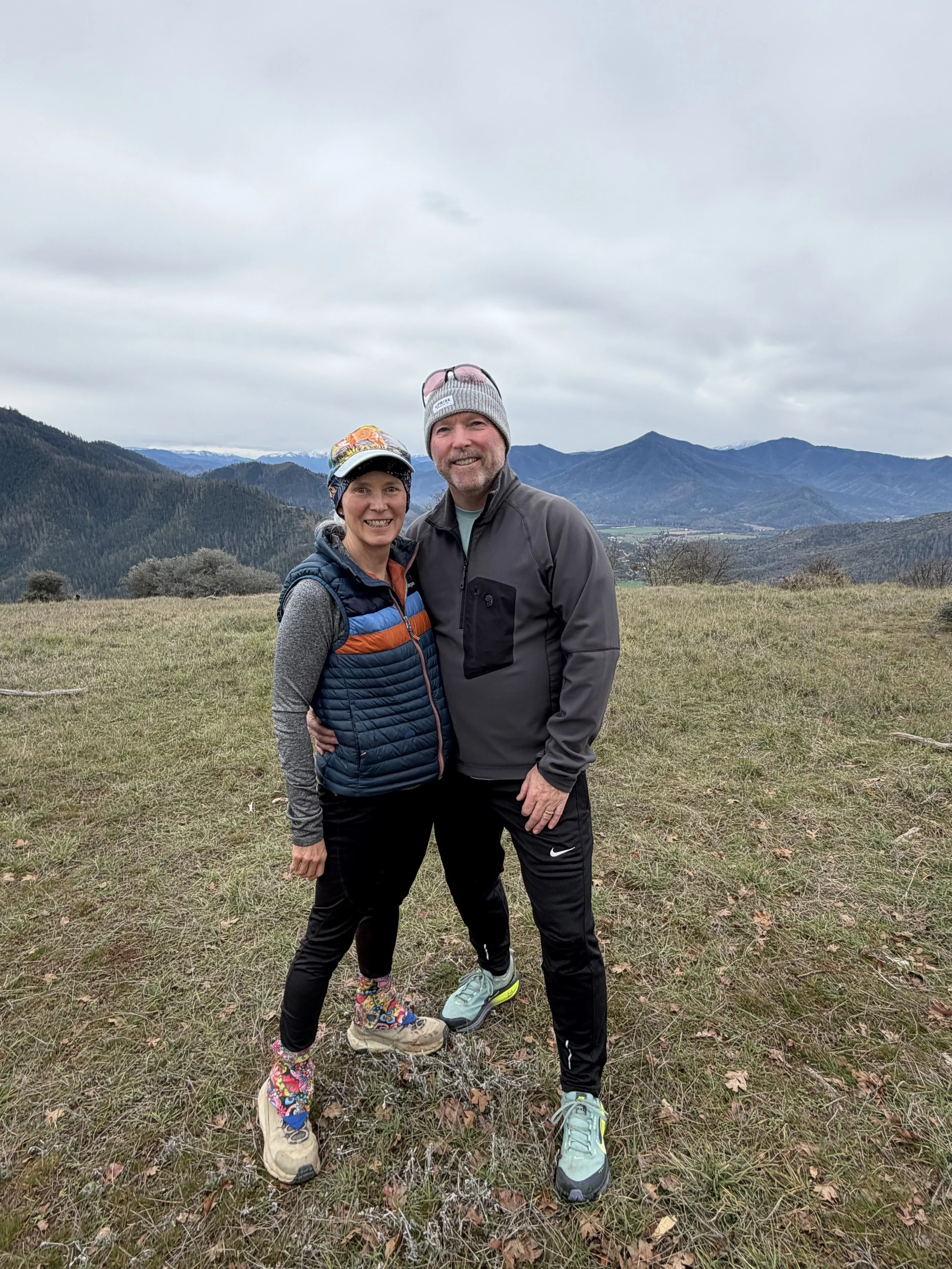 Midlife couple standing on a mountain overlook during a hike, representing movement and vitality after menopause.