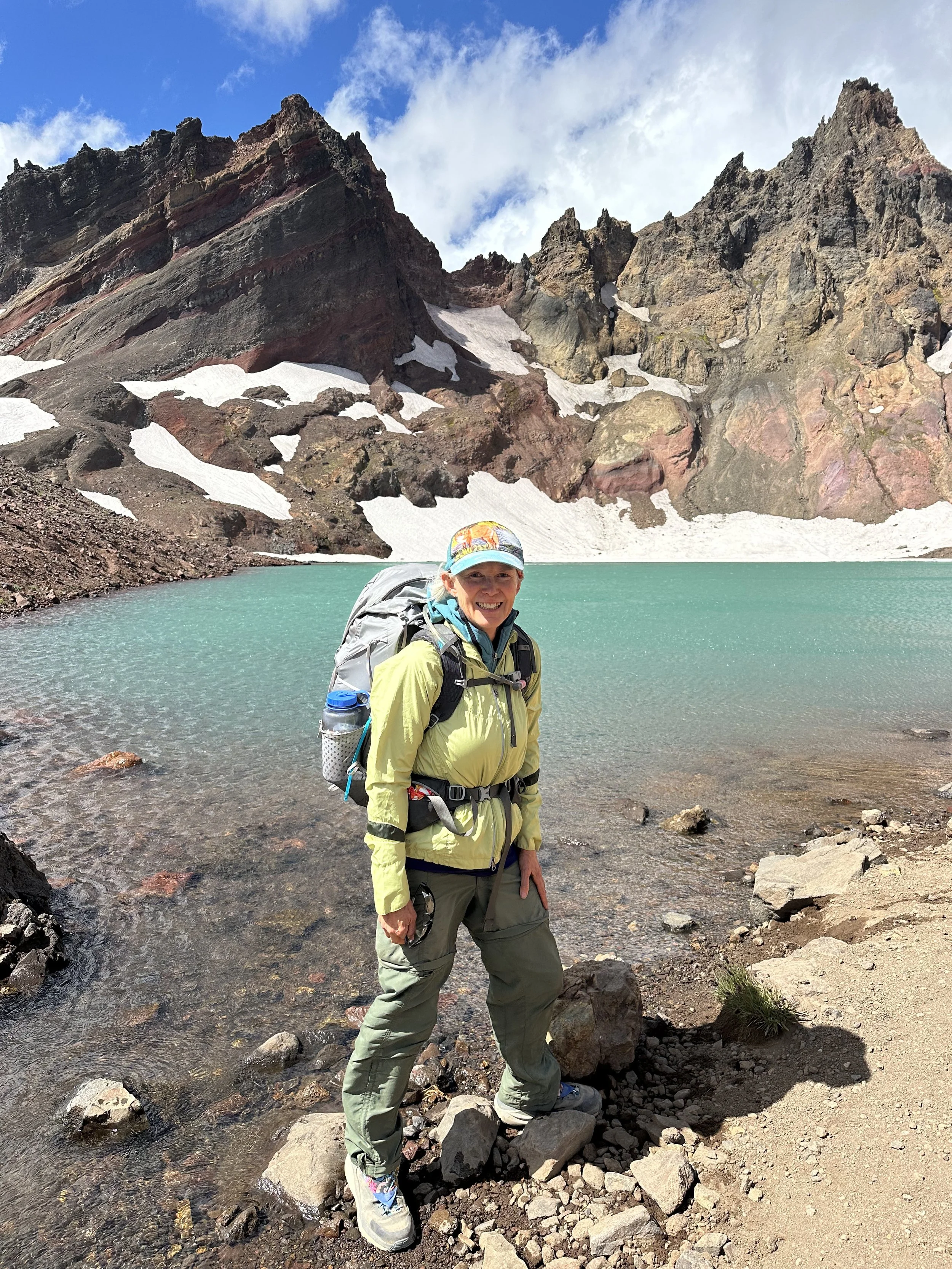 Menopause wellness coach backpacking beside an alpine lake, reflecting strength, vitality, and confidence in midlife.