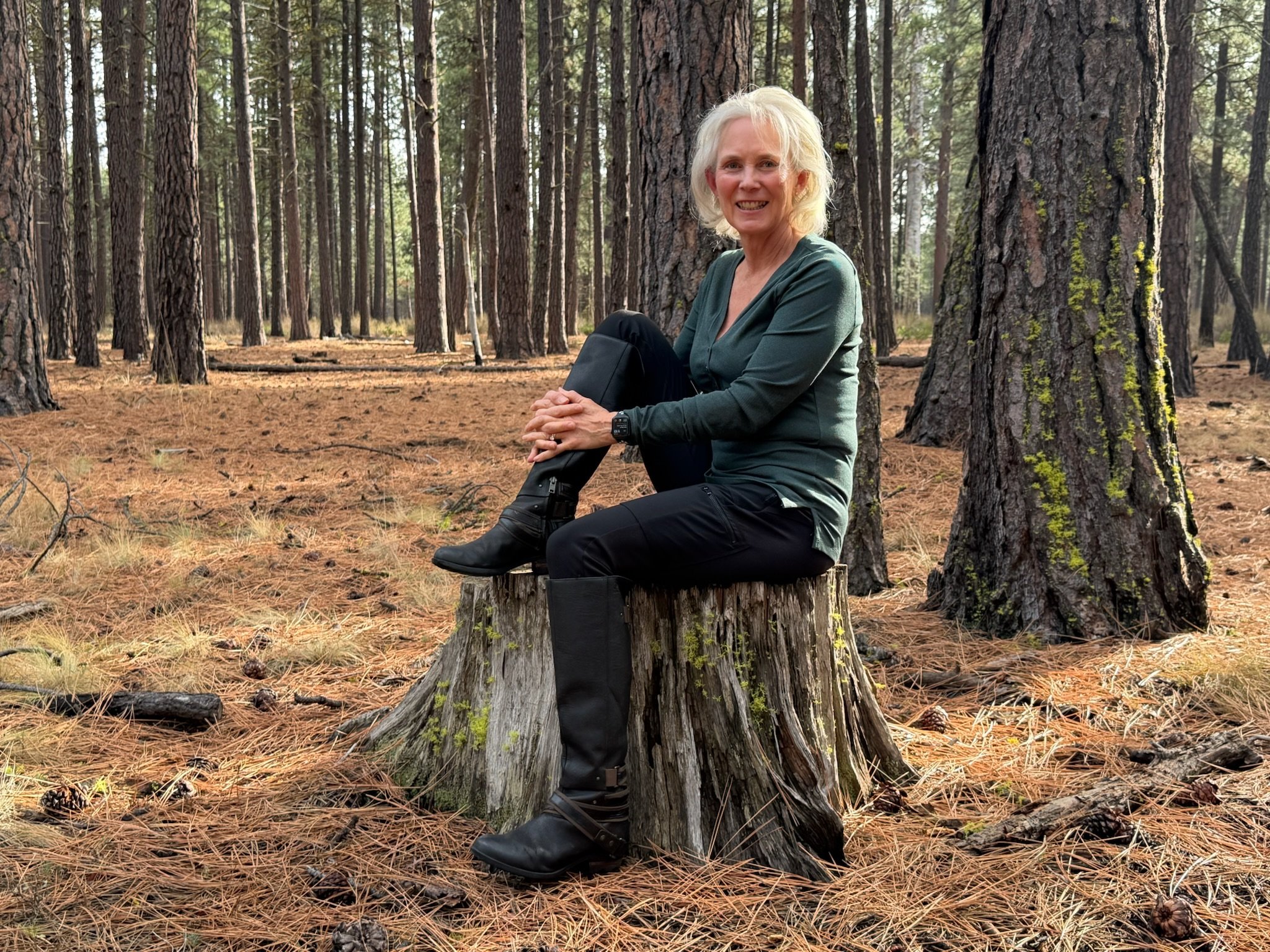 Midlife woman sitting on a rocky overlook, reflecting on health, vitality, and life transitions in nature.