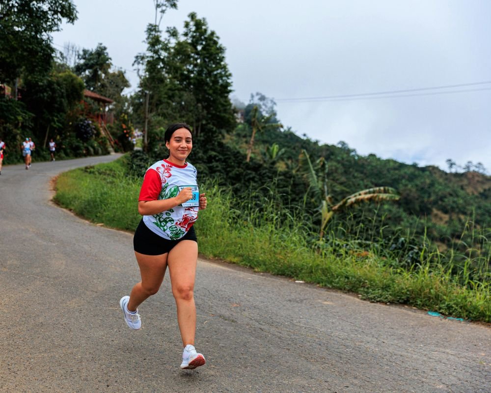 A woman doing a fun run on the road, smiling as she runs
