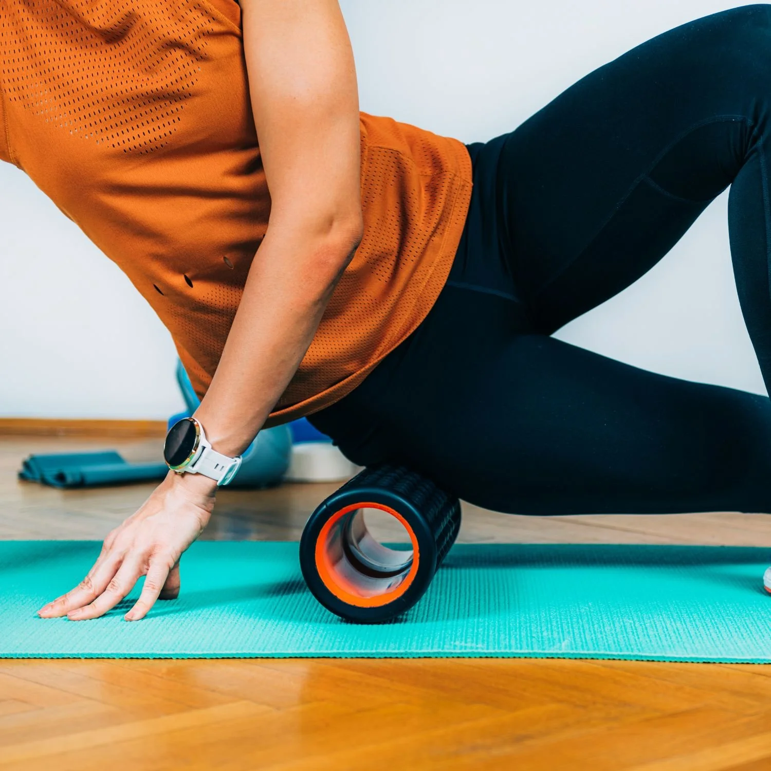 Woman uses a foam roller on the outside of her thigh targeting the glutes, TFL and ITB