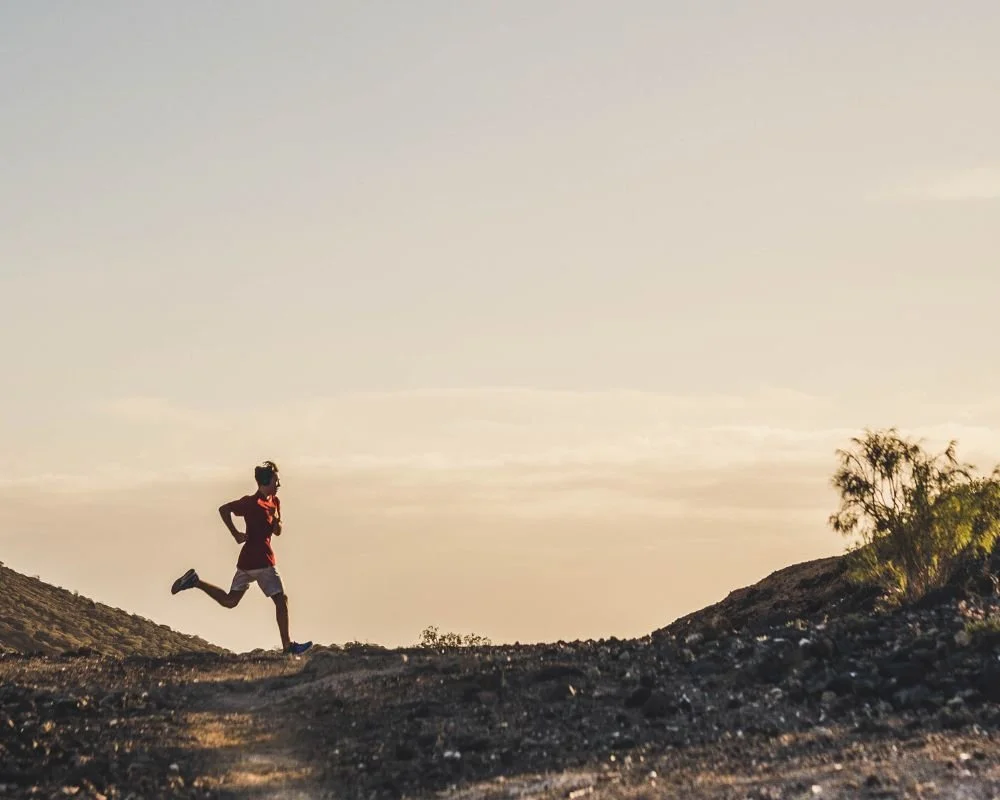 A man outside trail running at sunset