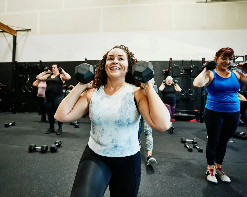 A group of women in the gym using weights and resisted exercise to help treat their ITB pain from ITBS