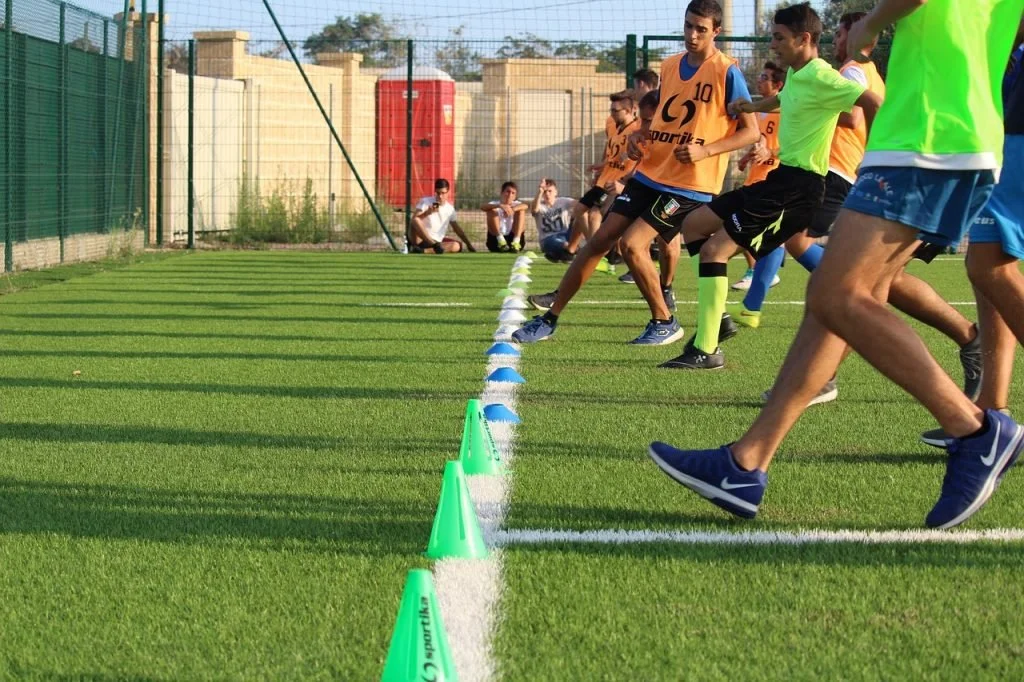 A young boy's sports team does running drills, using their balance to not fall over