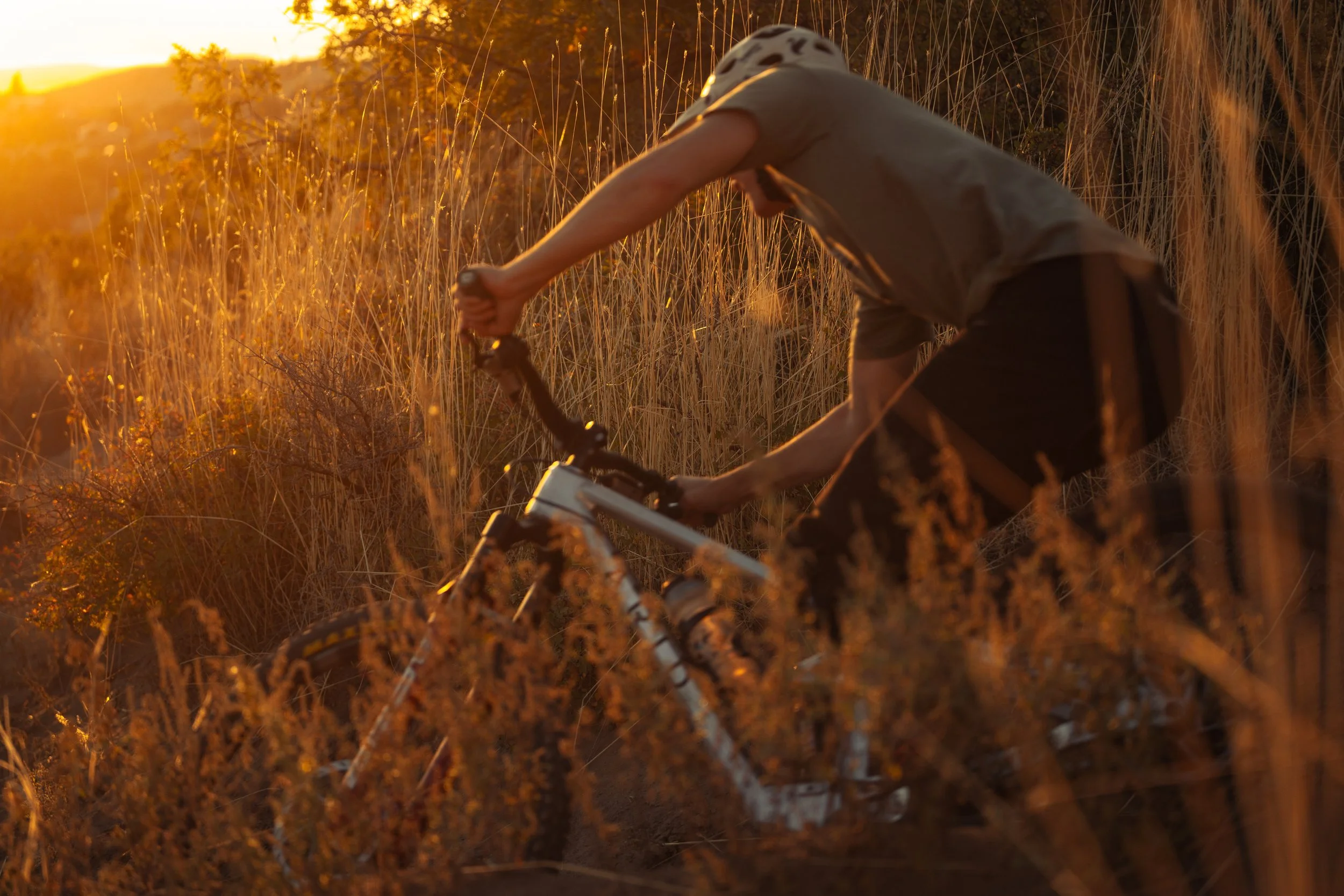 Mountain biker riding through tall grass at sunset on a ARID Bike | Photography by Anders Henrikson Photo 