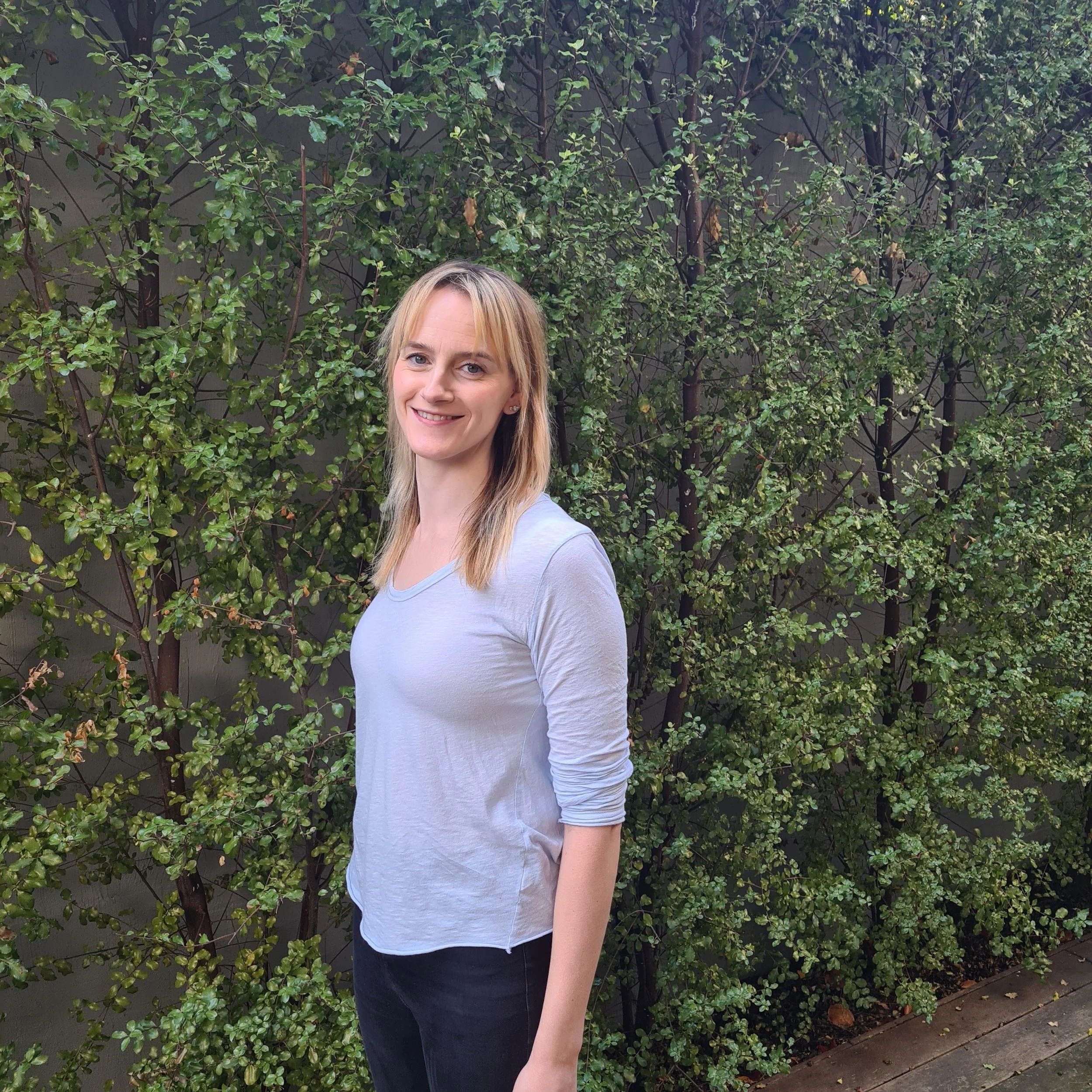 Kirsten standing next to a green hedge