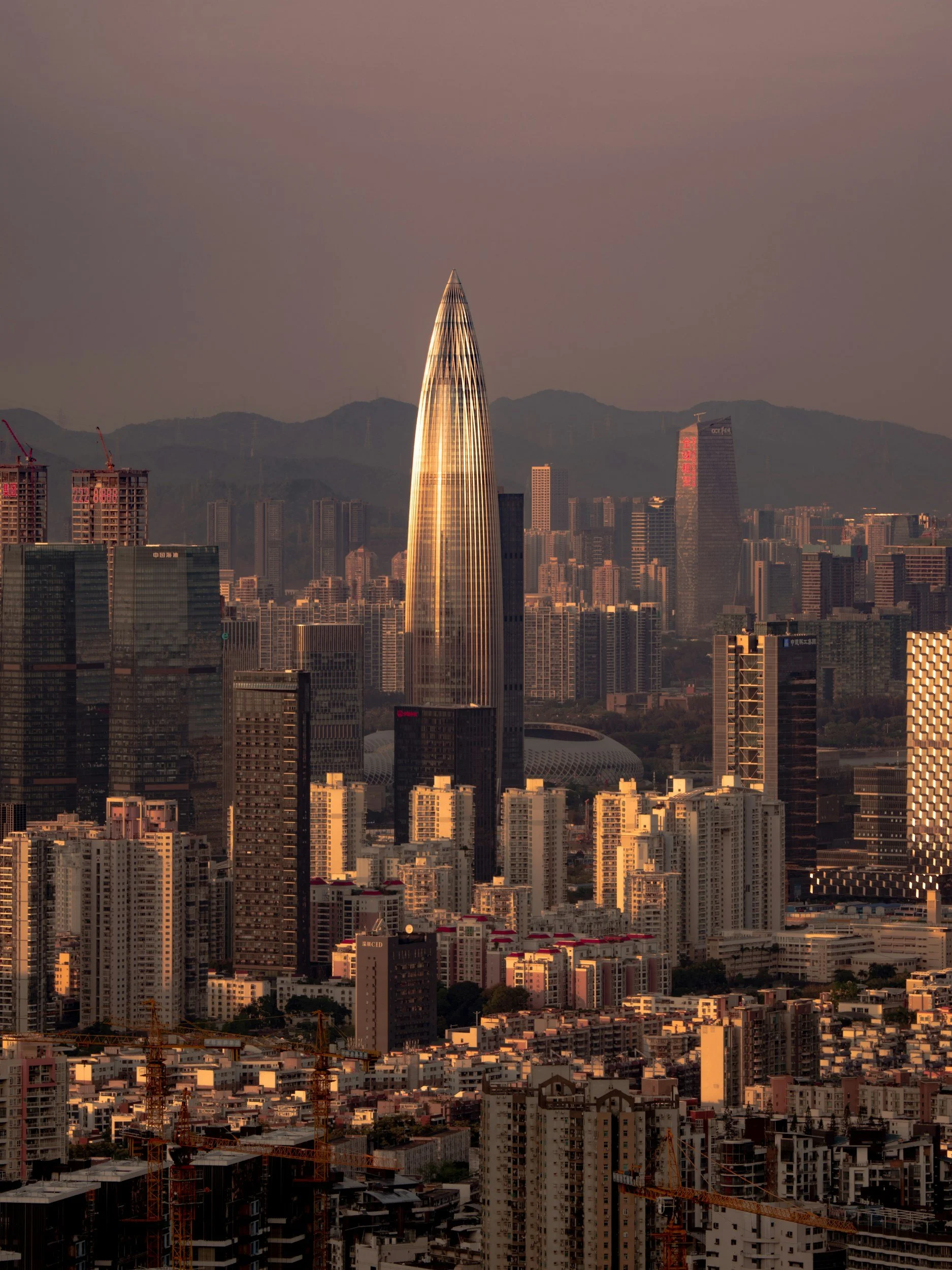 Nighttime cityscape of a densely populated urban area with illuminated skyscrapers and mid-rise buildings, featuring the tall, narrow skyline of the city.