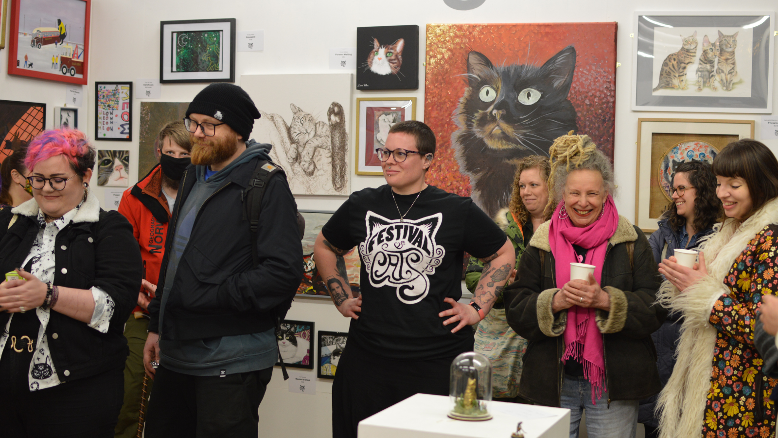 Group of people in an exhibition surrounded by cat art