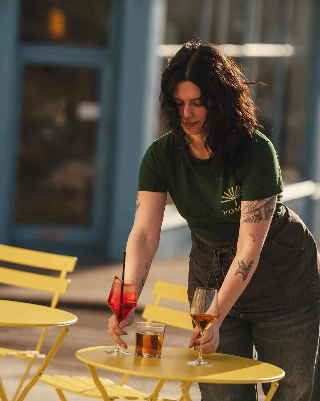 Woman lays yellow table outside hotel with drinks