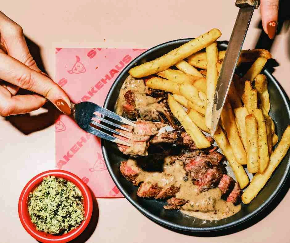Close up of hands eating steak frites from above