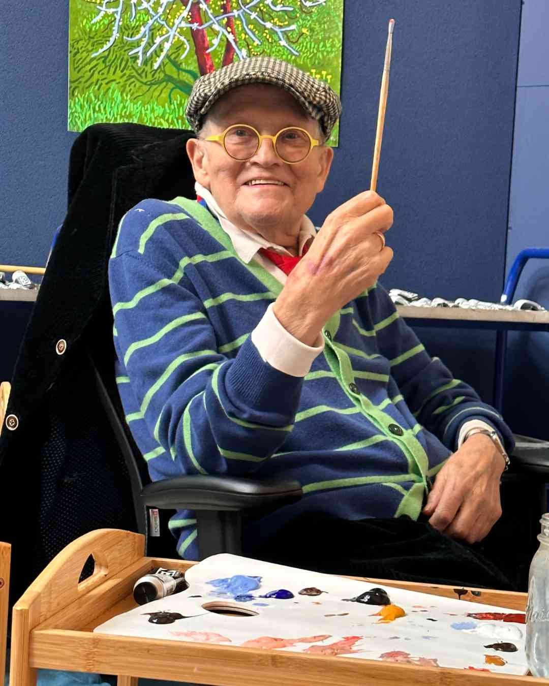 old man in striped top holding a paintbrush