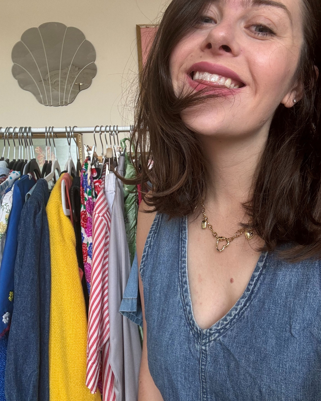 close up of woman with dark hair and denim in front of row of clothes