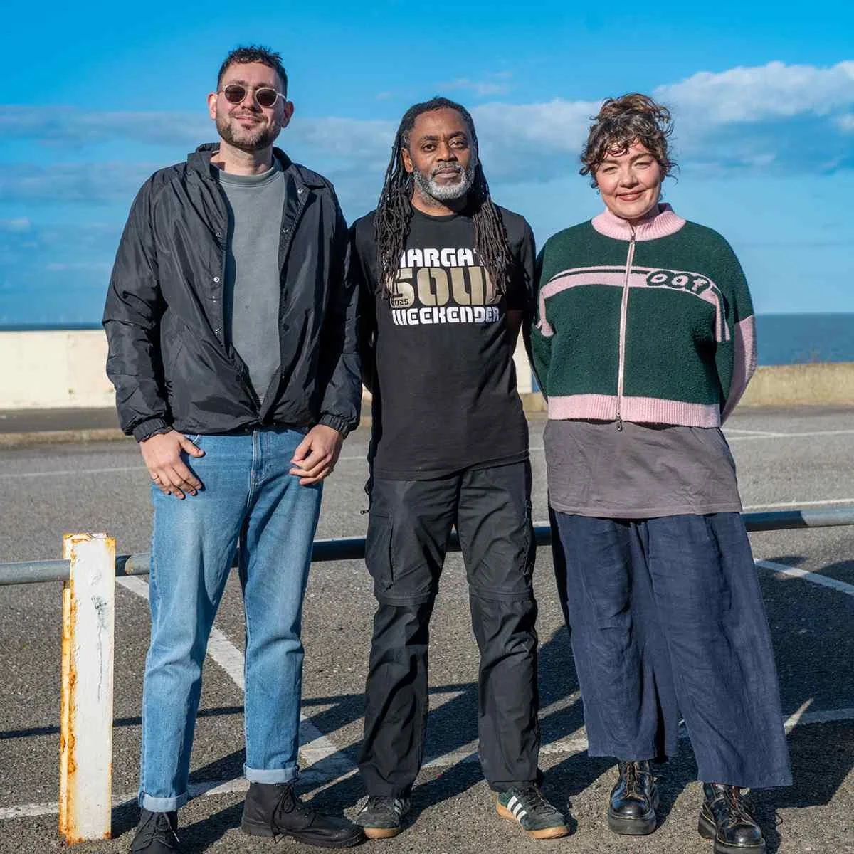 one white woman and man and a black man stood in front of the sea