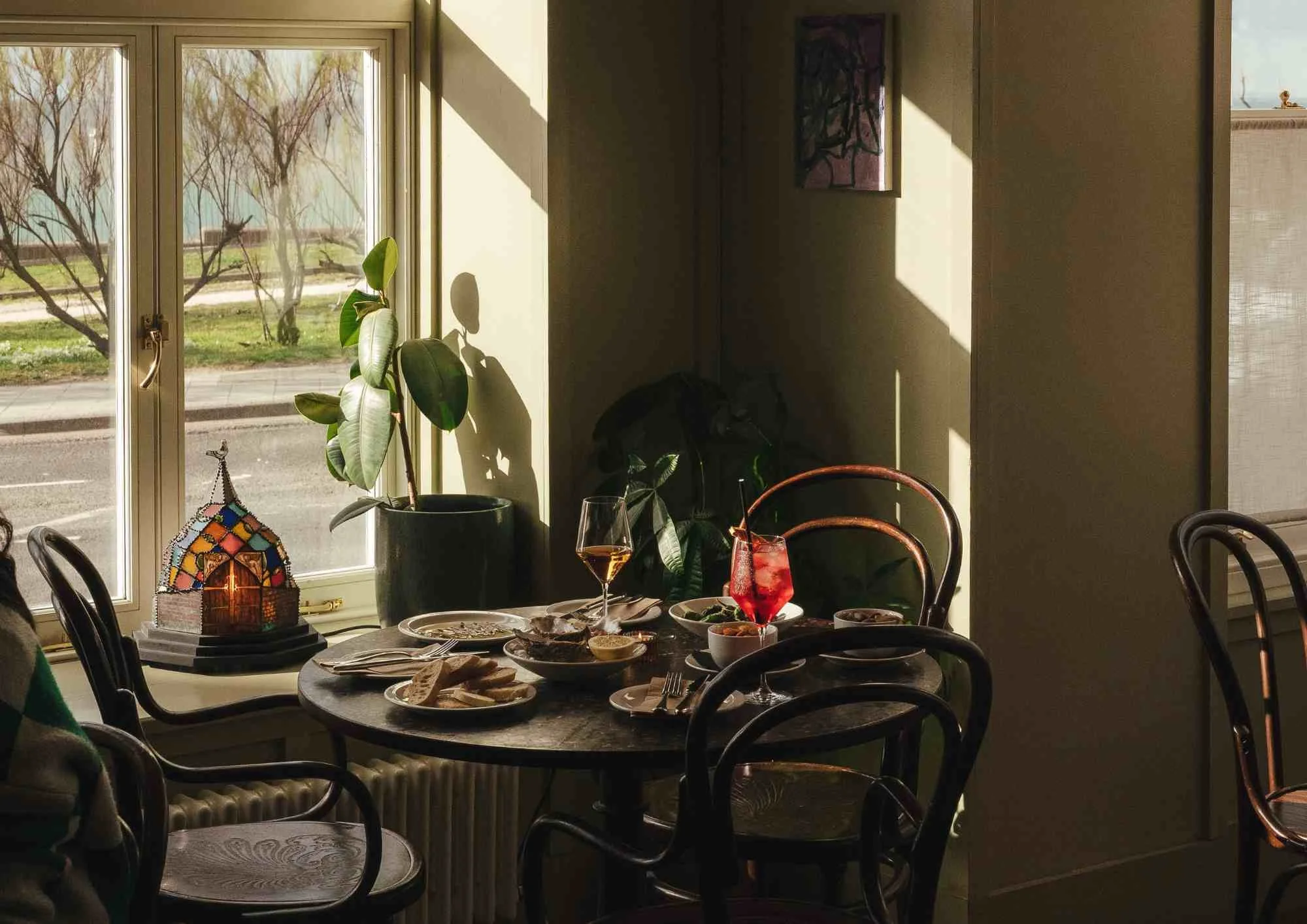 Table set for lunch with wooden chairs in window with light coming in