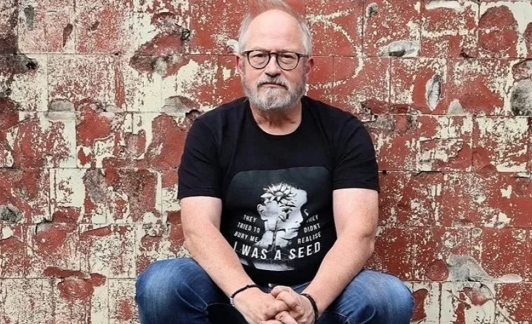 Pic of a white middle aged man against a brick wall