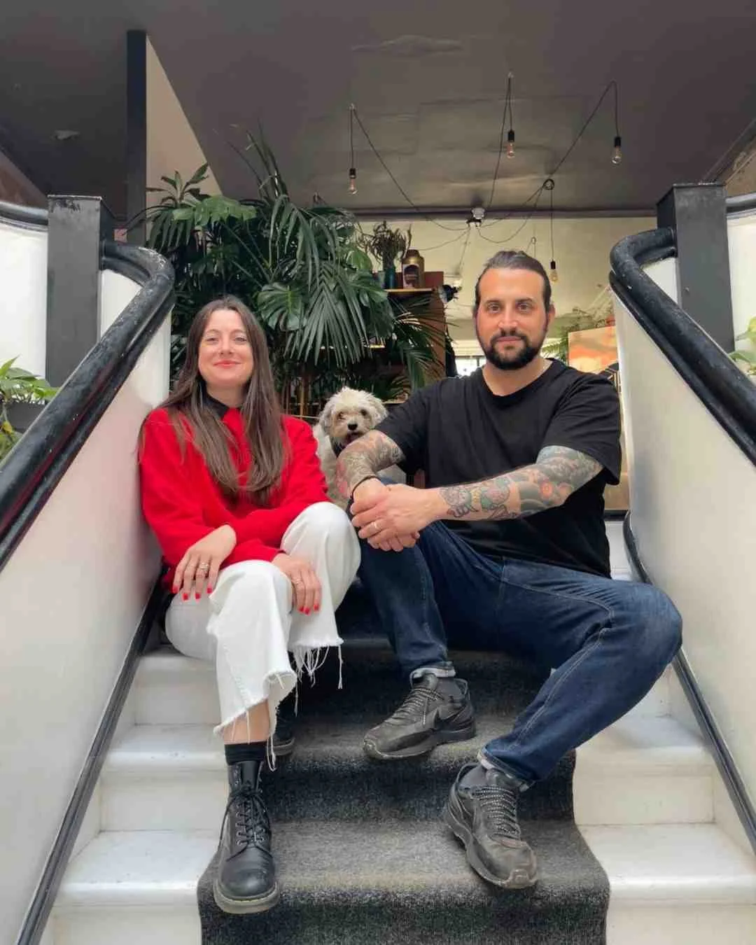 Man and woman sit on stairs in the cafe with their dog