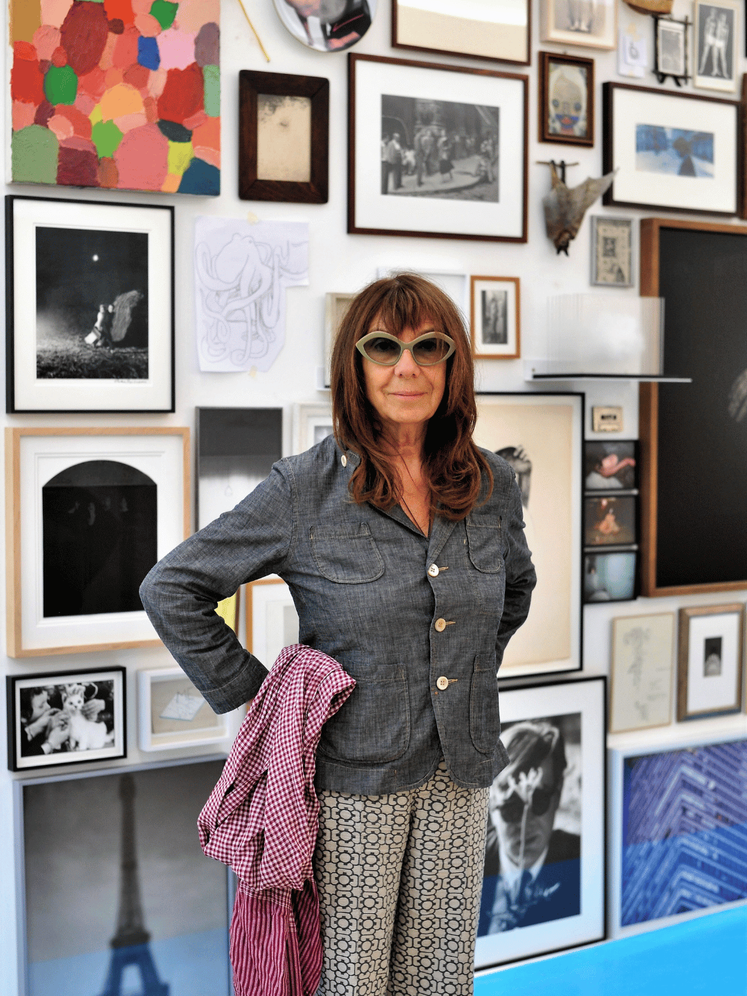 Woman - sophie calle - in sunglasses standing in front of a wall of art