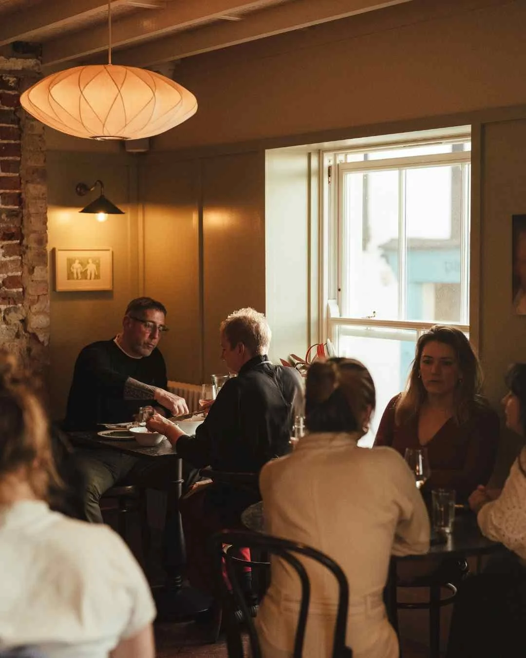 Groups of diner in a sepia toned restaurant with wooden bistro chairs