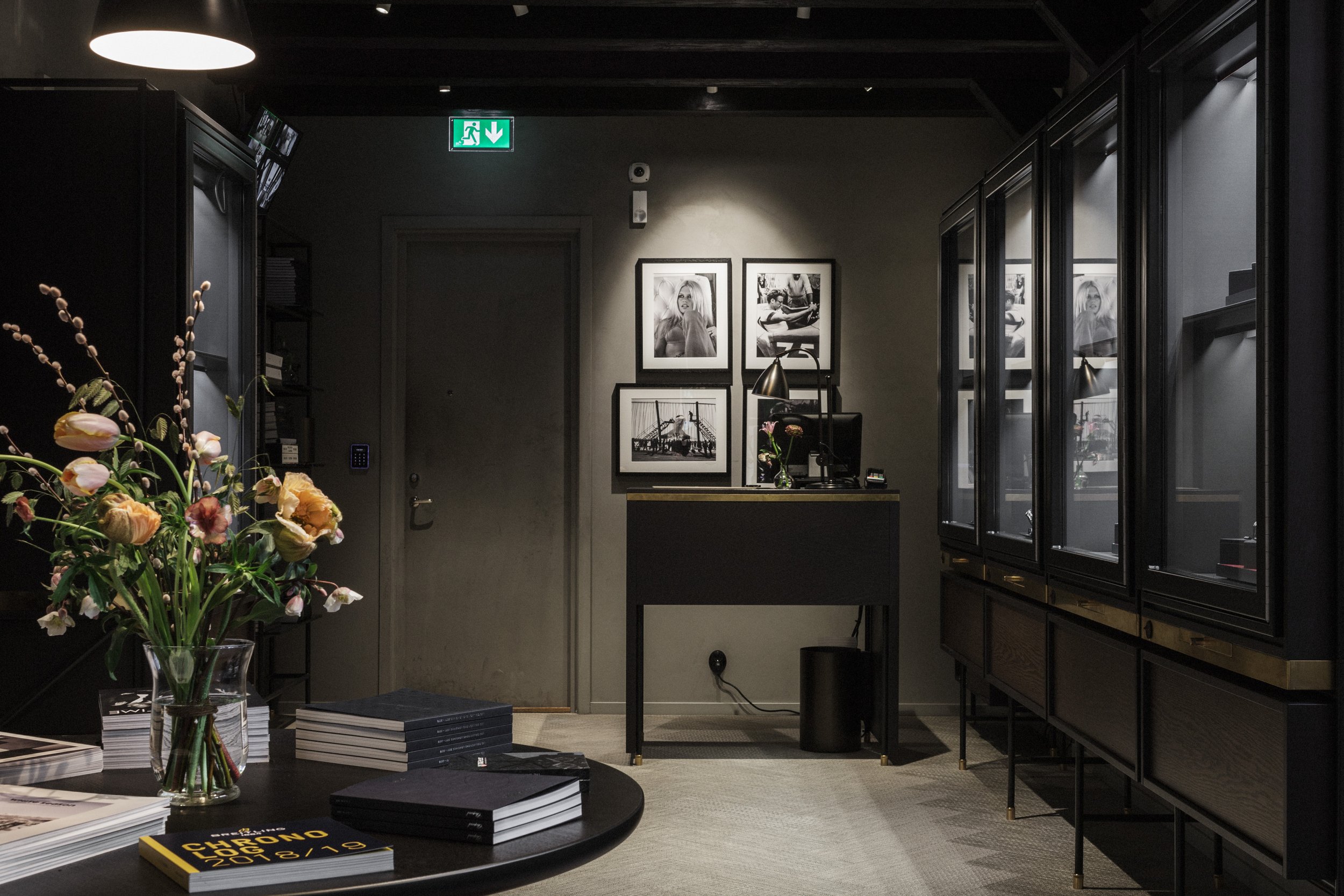 Runt bord med en stor blombukett med tulpaner och svartvita fotografier på väggarna.