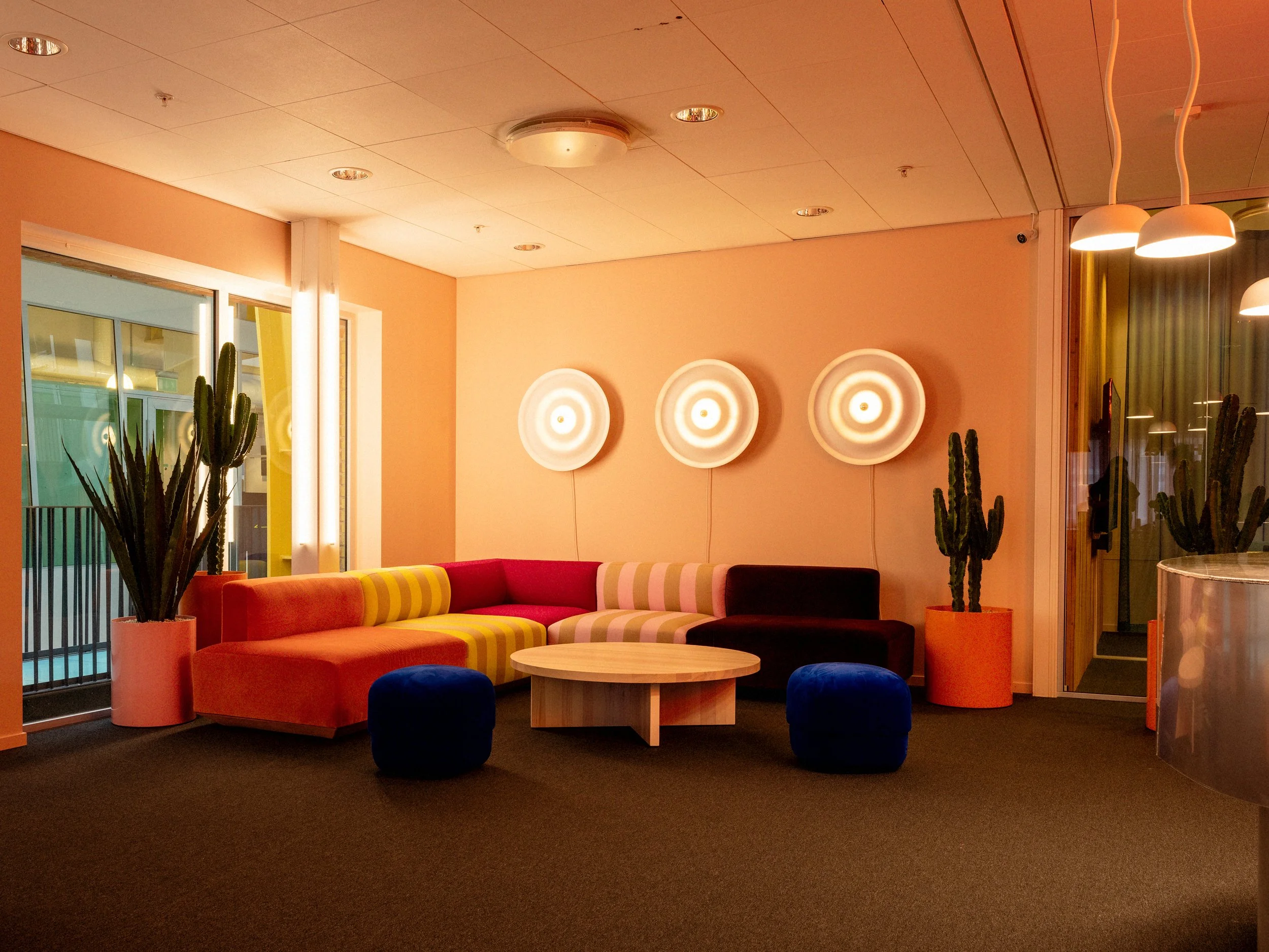 Loungeyta med färgglad tyger, puffar från Norrman Copenhagen och vägglampor från Wästberg.