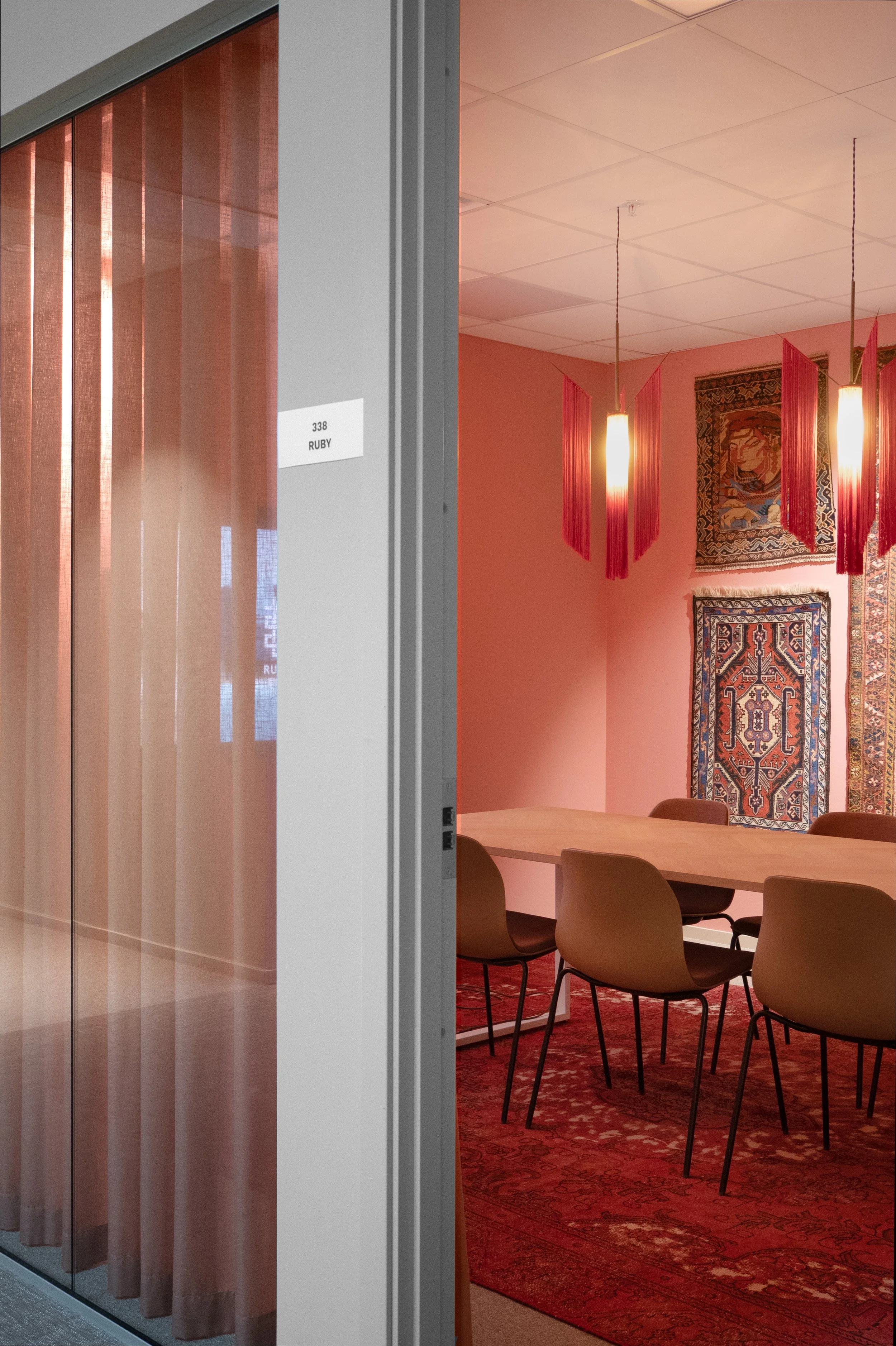 Mötesrum med orientaliska mattor, rosa väggar och textila detaljer