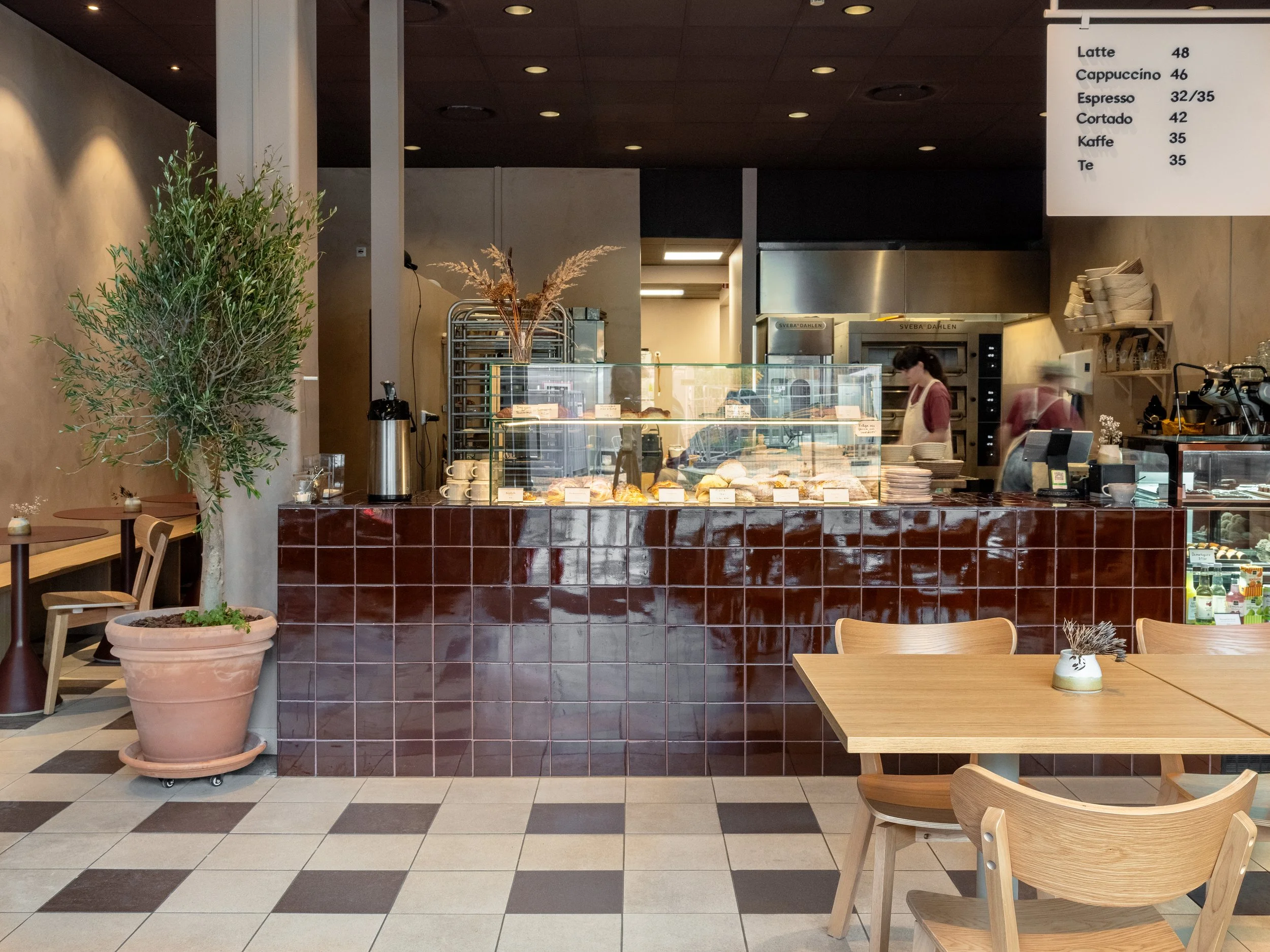 Bakery counter with pastries and bread at Bageri Baka, featuring an open bakery, tiled surfaces and wooden seating.