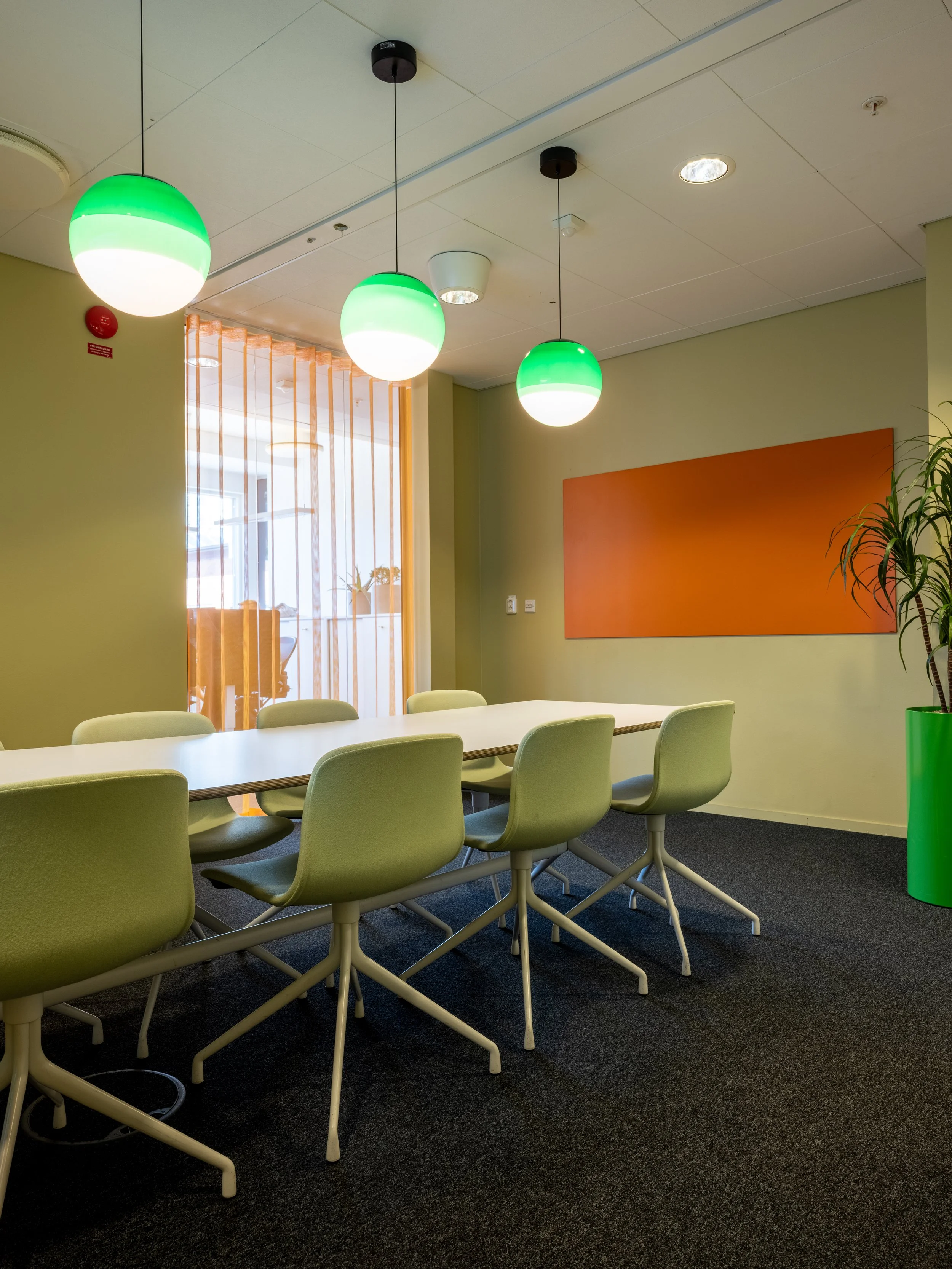 Mötesrum med stolar från Hay och en orange skrivtavla.