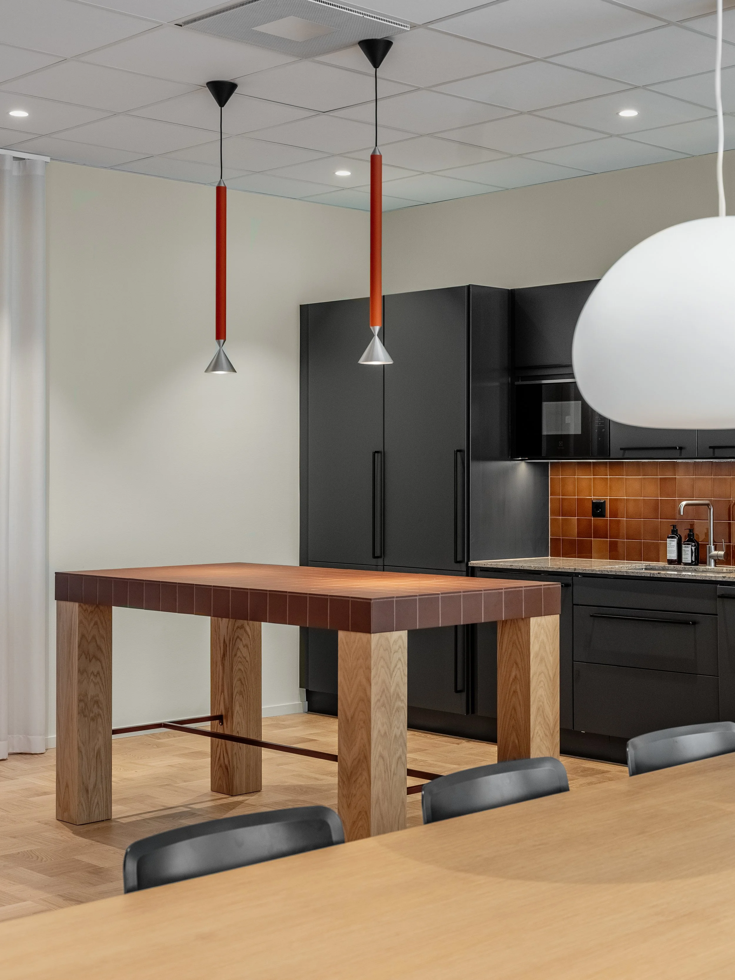 Office kitchen with built-in kitchen island, wood details, dark cabinetry and brown tiles