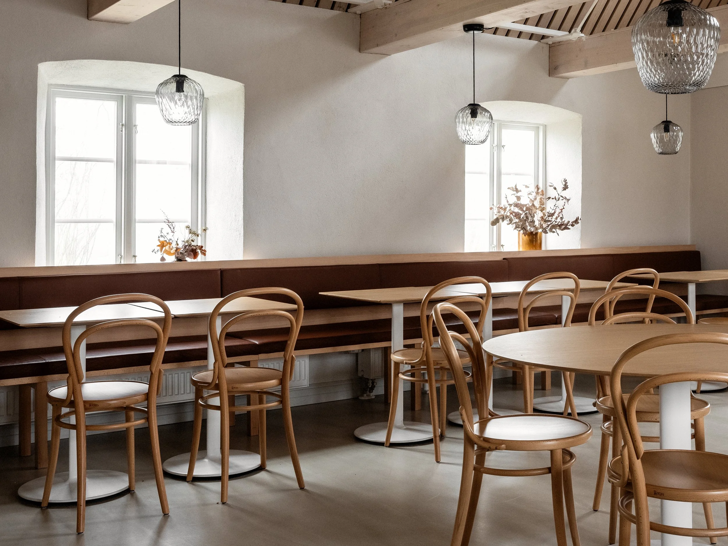 Platsbyggd soffa i ek och dyna i brunt läder. Stolar från Thonet och taklampor i glas från &tradition.