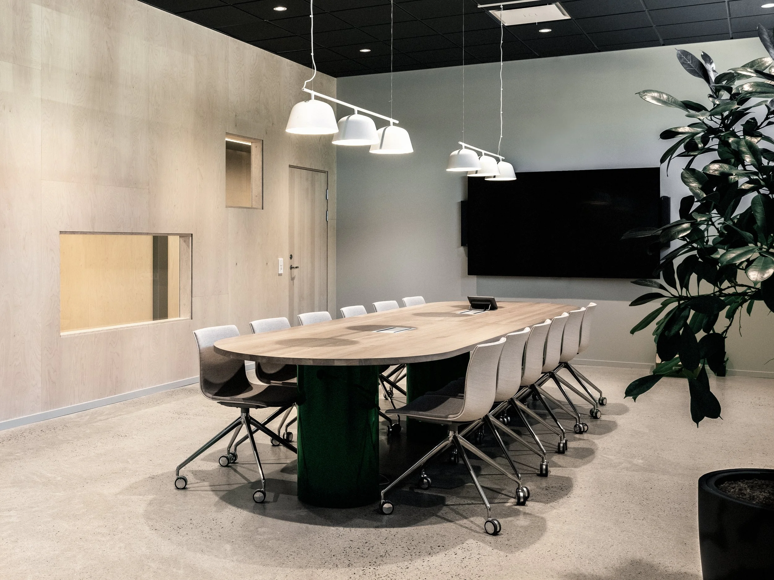 Mötesrum med specialritat bord och vita taklampor och väggar av plywood.