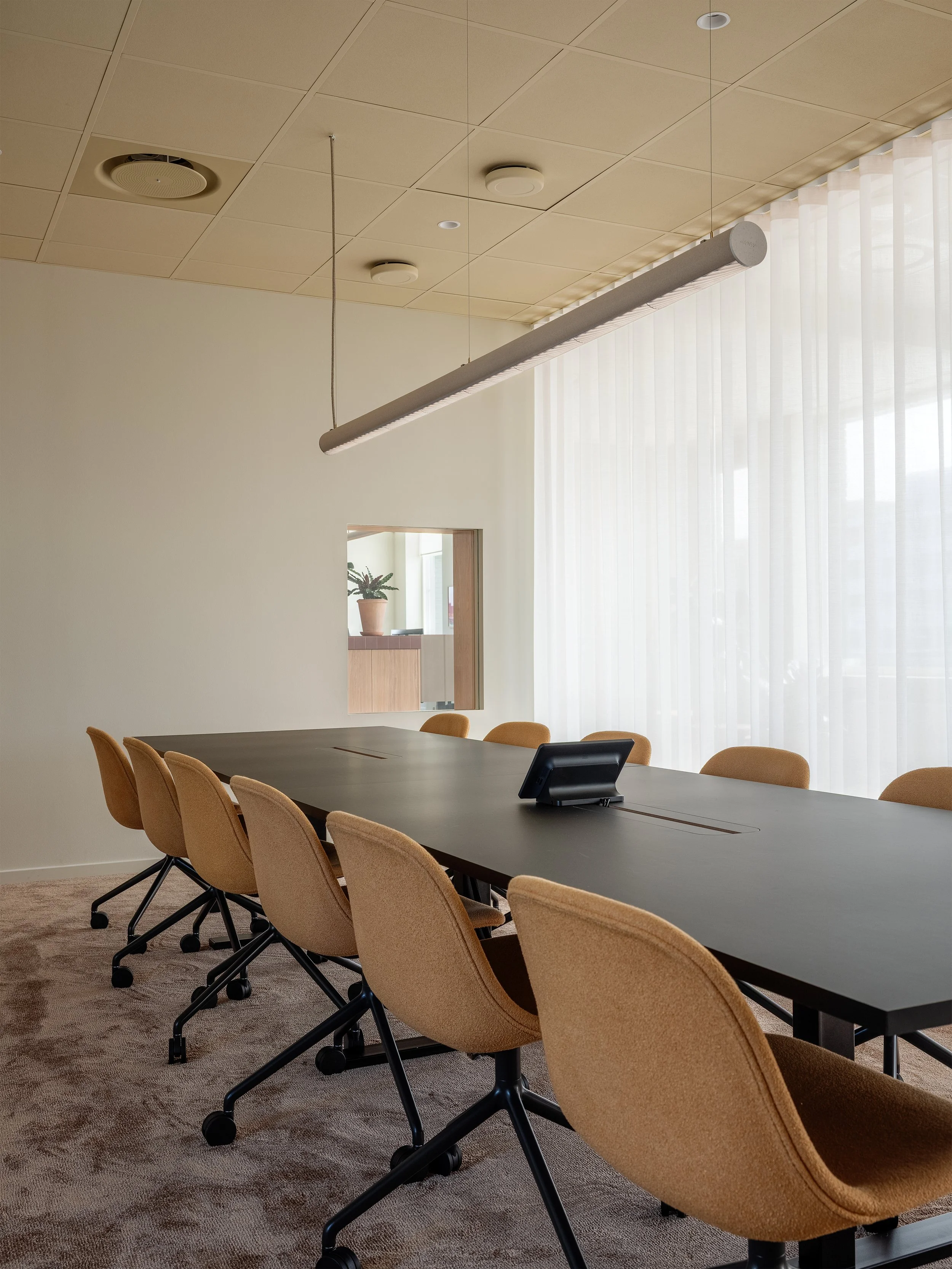Mötesrum med långt konferensbord, stoppade stolar, målade undertak och mjukt dagsljus