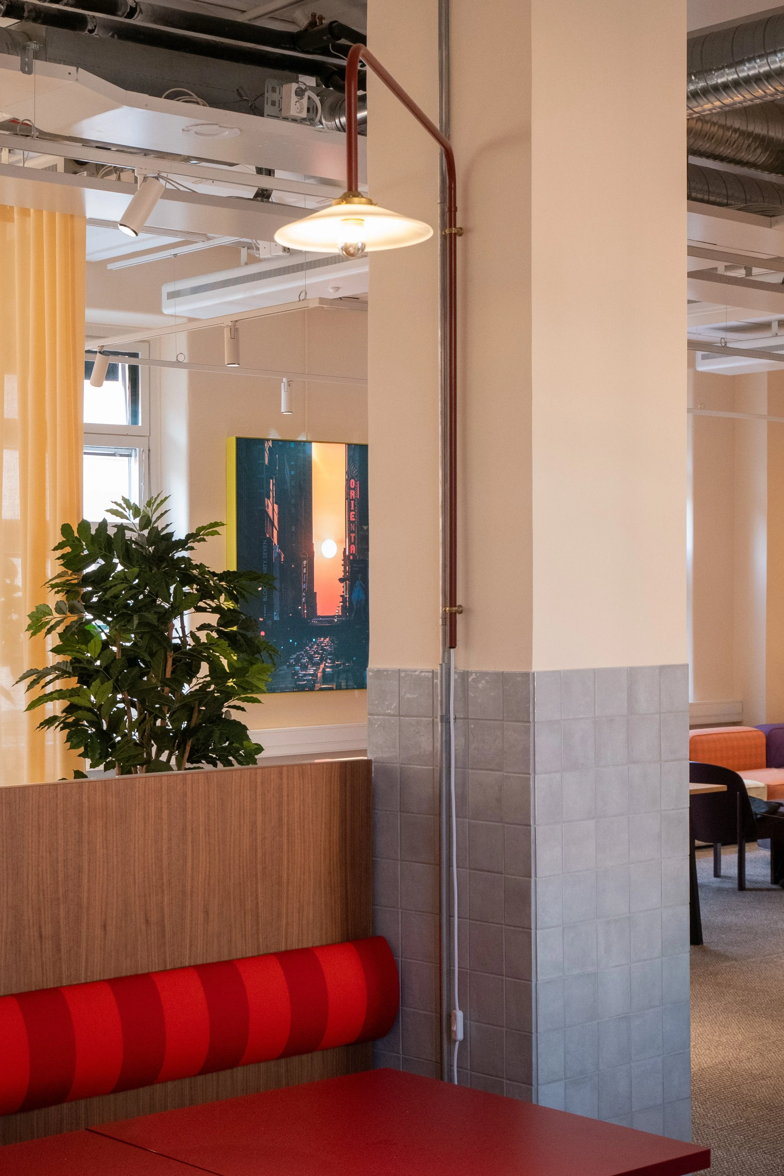 Specialritad och designad soffa med ryggdyna i rött randigt tyg. Pelare kaklad i en blank grå platta för intressanta kontraster. Väggarmatur från Valerie Objects i klarröd kulör.