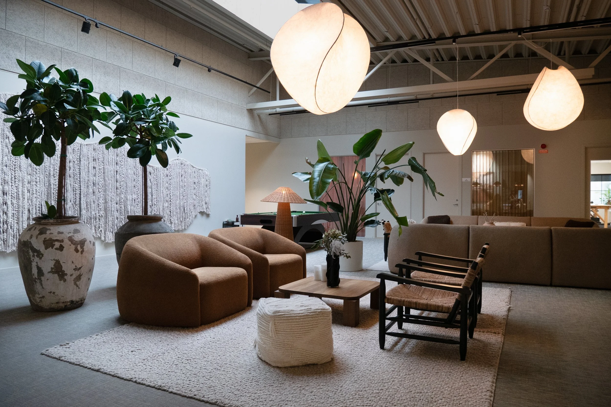 Loungeyta med soffgrupper, stora växter och textila vägginstallationer
