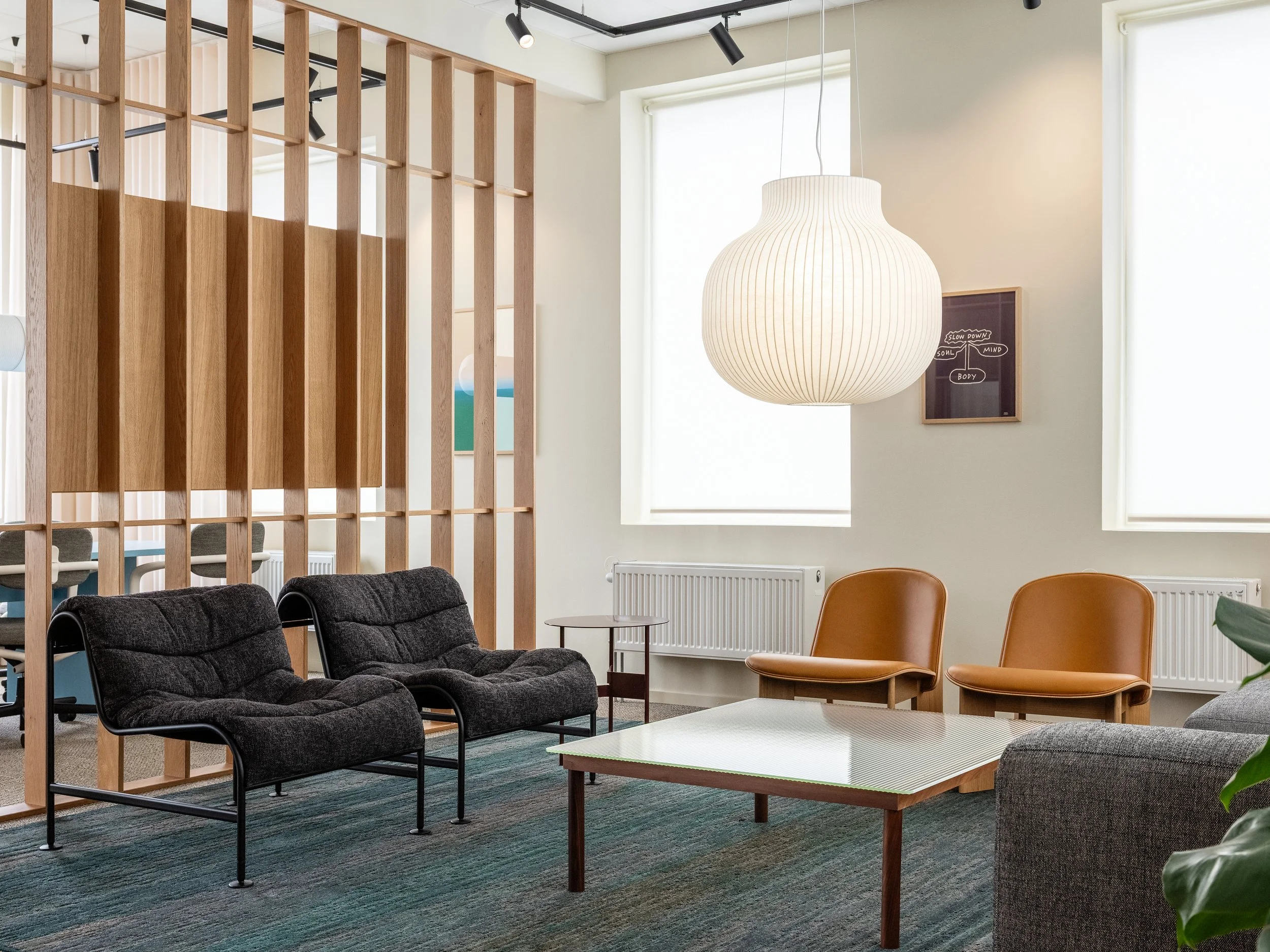 Lounge area with soft seating, wooden partition and subdued lighting in an office environment