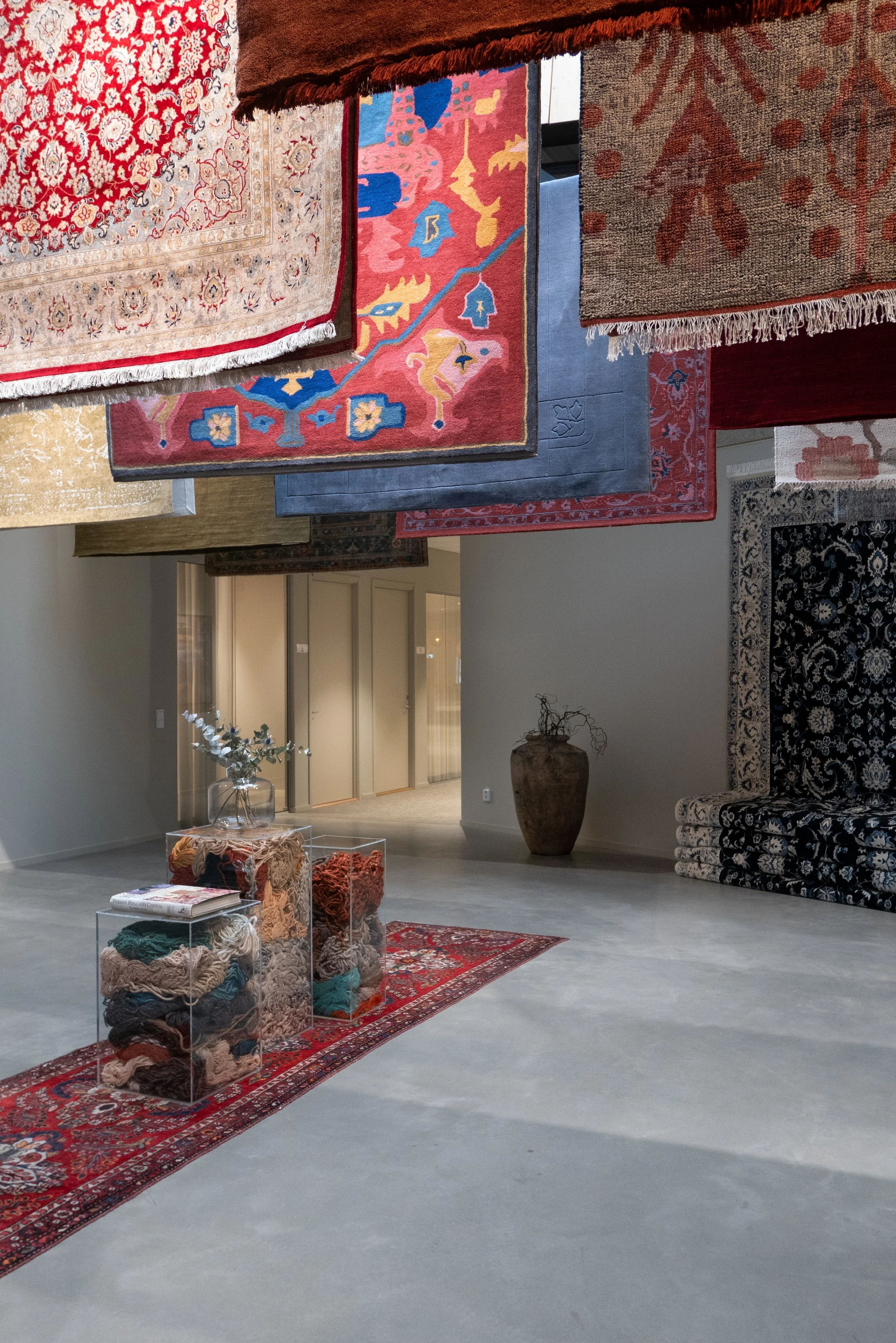 Entré med hängande orientaliska mattor och utställning i Rugvistas kontor