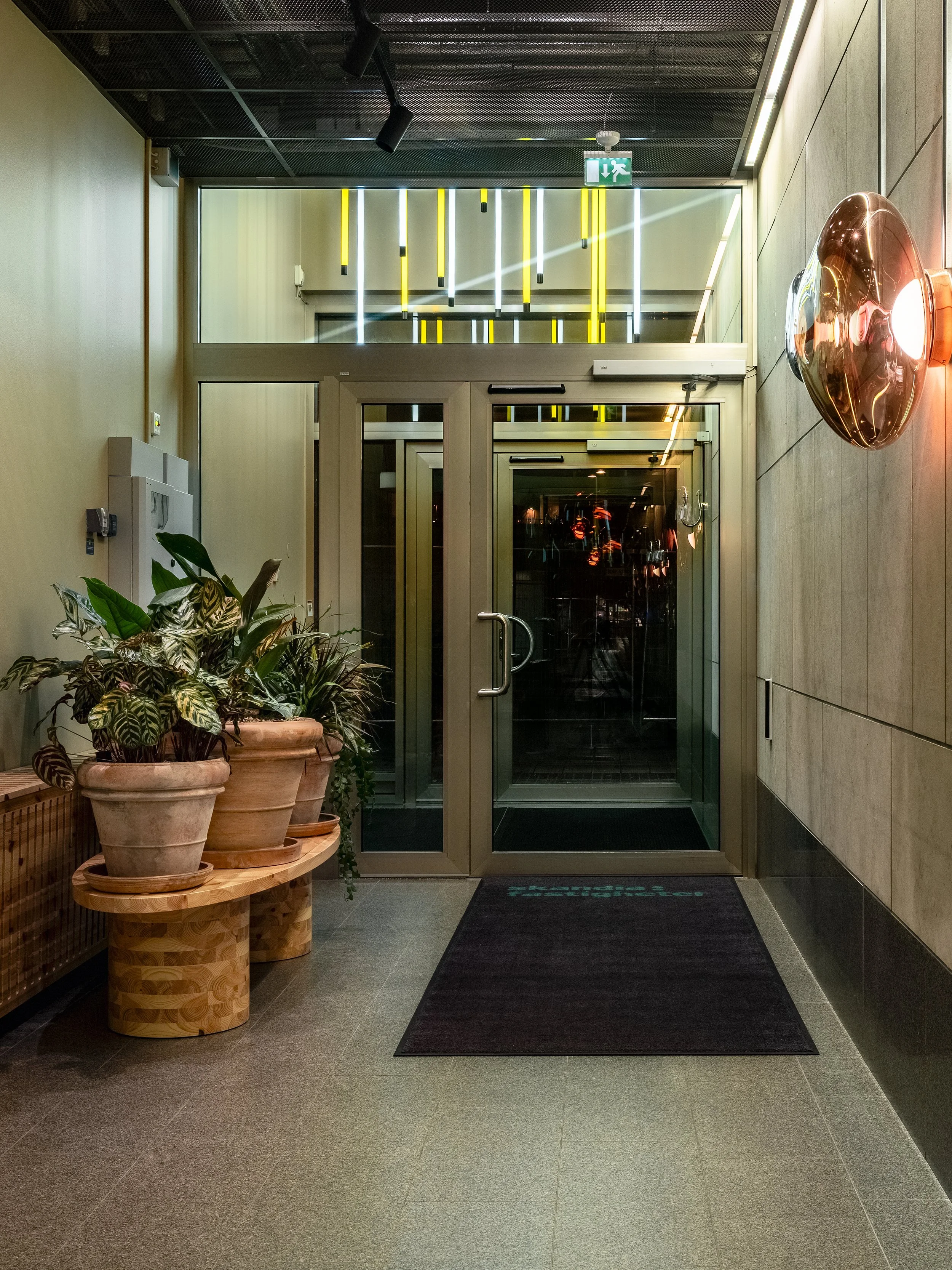 Exterior entrance with glazed doors, planters, entrance mat and lighting in a warm colour palette