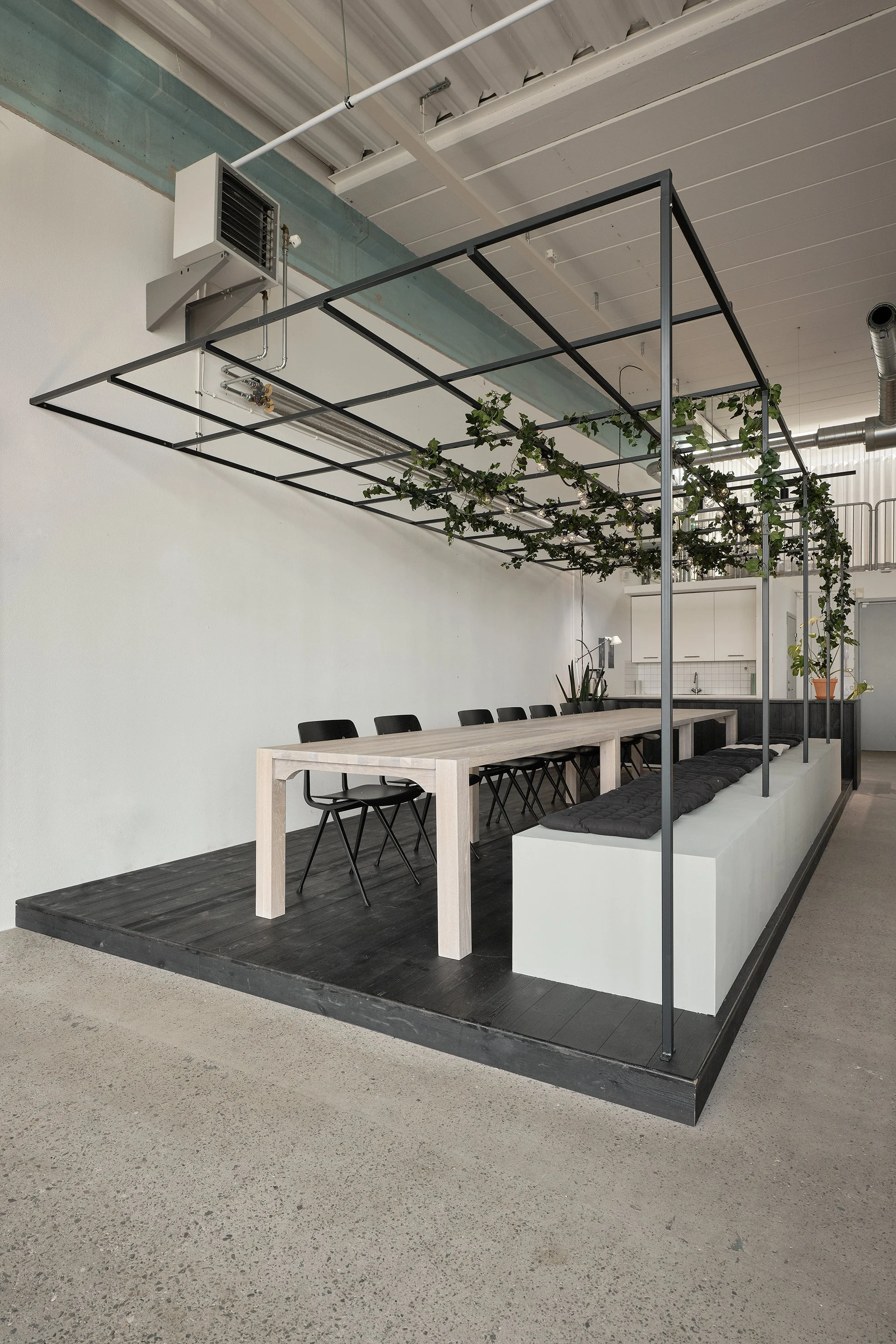 Långbord i trä under metallspaljé med klättrande murgröna