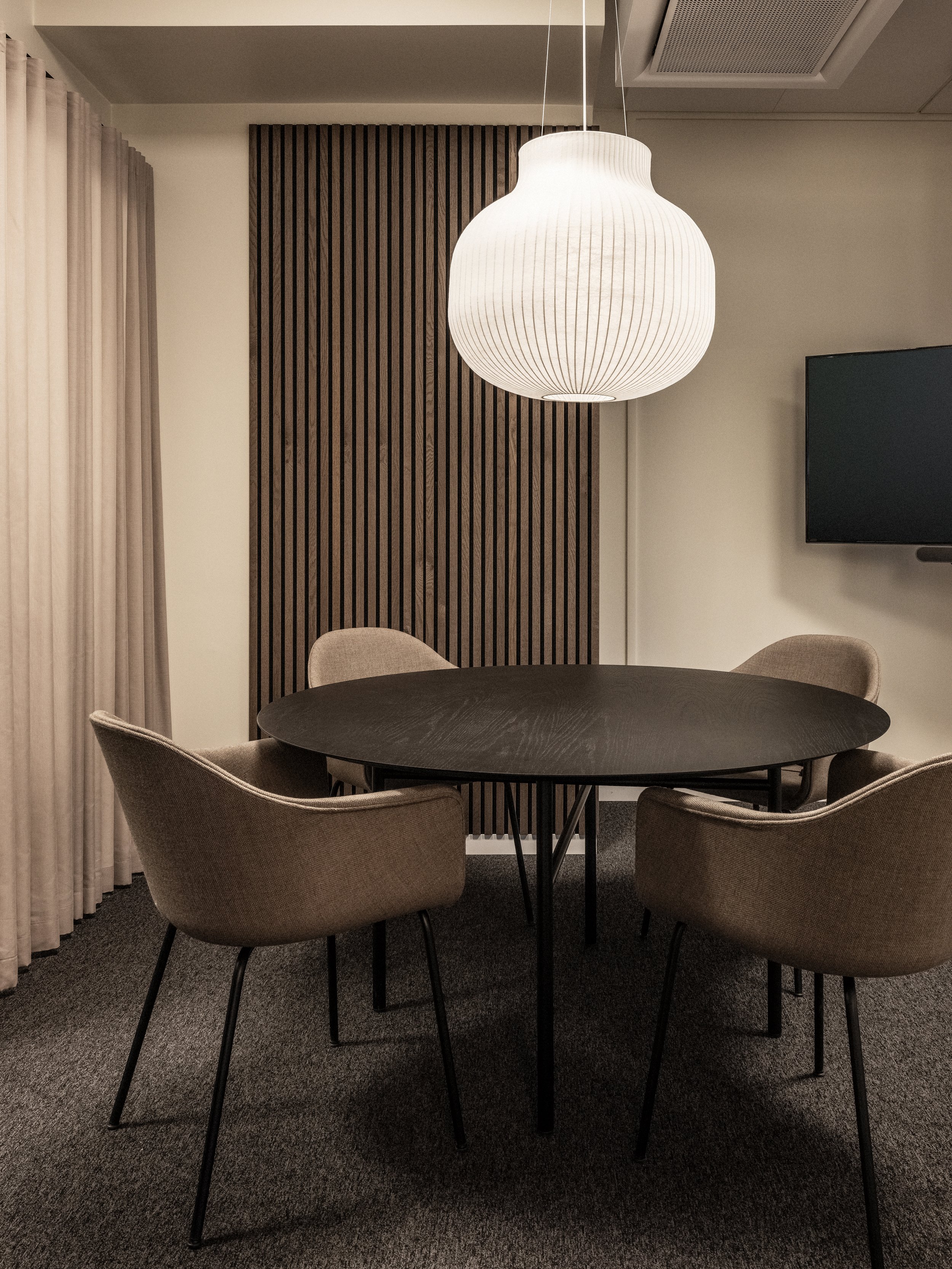 Mötesrum med nedpendlad lampa från Muuto och ribbpanel i trä.