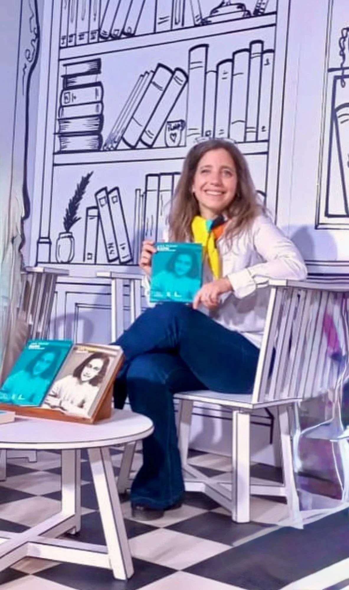 Una mujer con expresión emotiva, sentada en una silla de madera blanca, sosteniendo un libro con una portada azul que tiene una imagen de una mujer. El fondo y la mesa están decorados con dibujos de libros y muebles, simulando un ambiente de librería o biblioteca, en estilo de dibujo lineal.