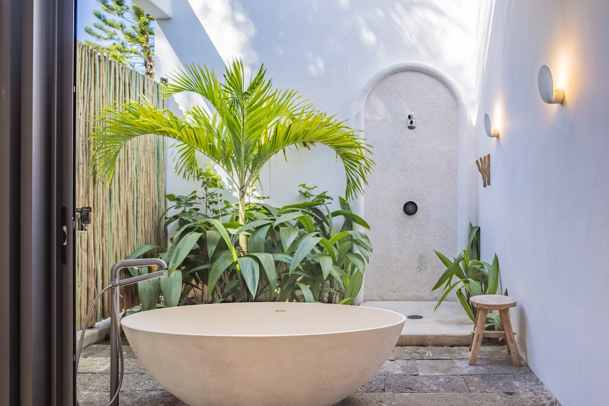 Tropical outdoor bathroom with a freestanding stone bathtub