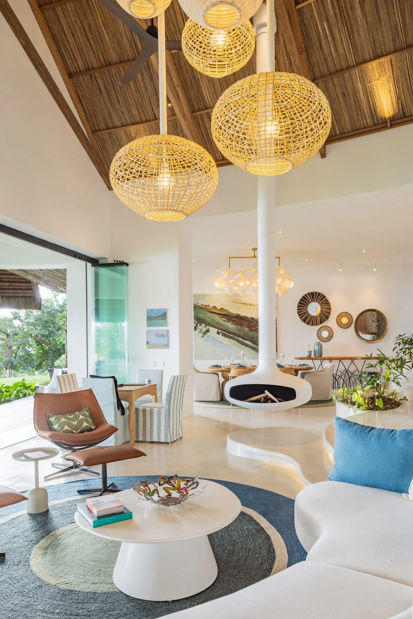 Sunken living room with suspended fireplace and woven pendant lights