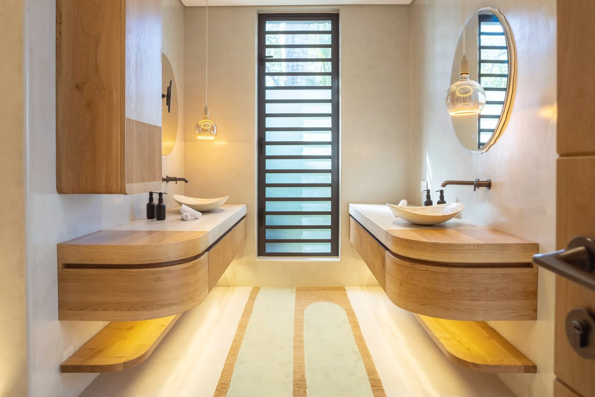 Warm timber double vanity bathroom with pendant lights and round mirrors