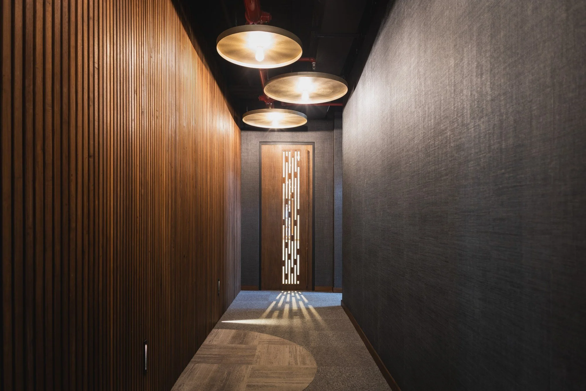 Couloir architectural de Strategia, habillage mural en bois et éclairage graphique.