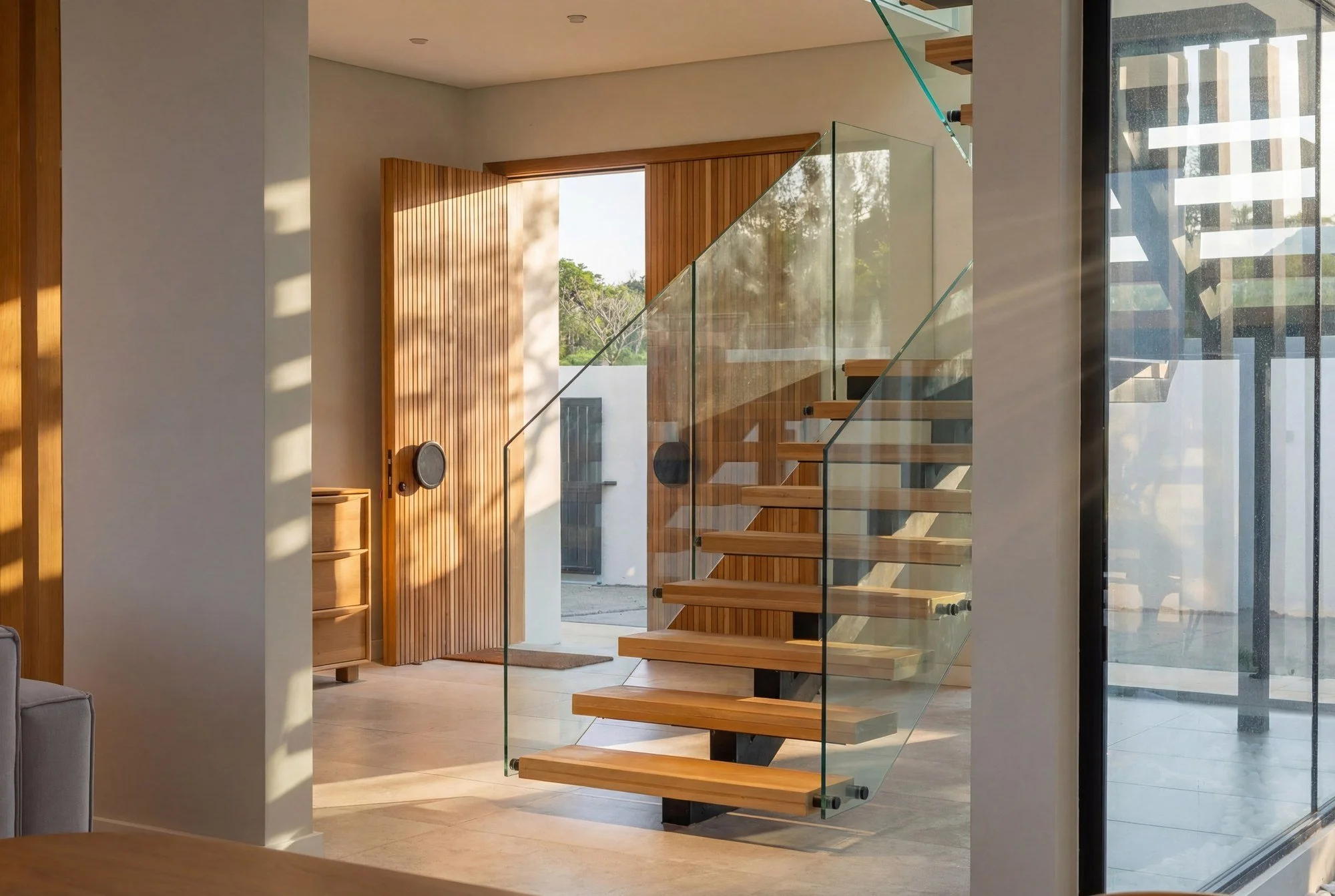 Escalier contemporain en bois et verre de la Chikooree House, baigné de lumière naturelle.