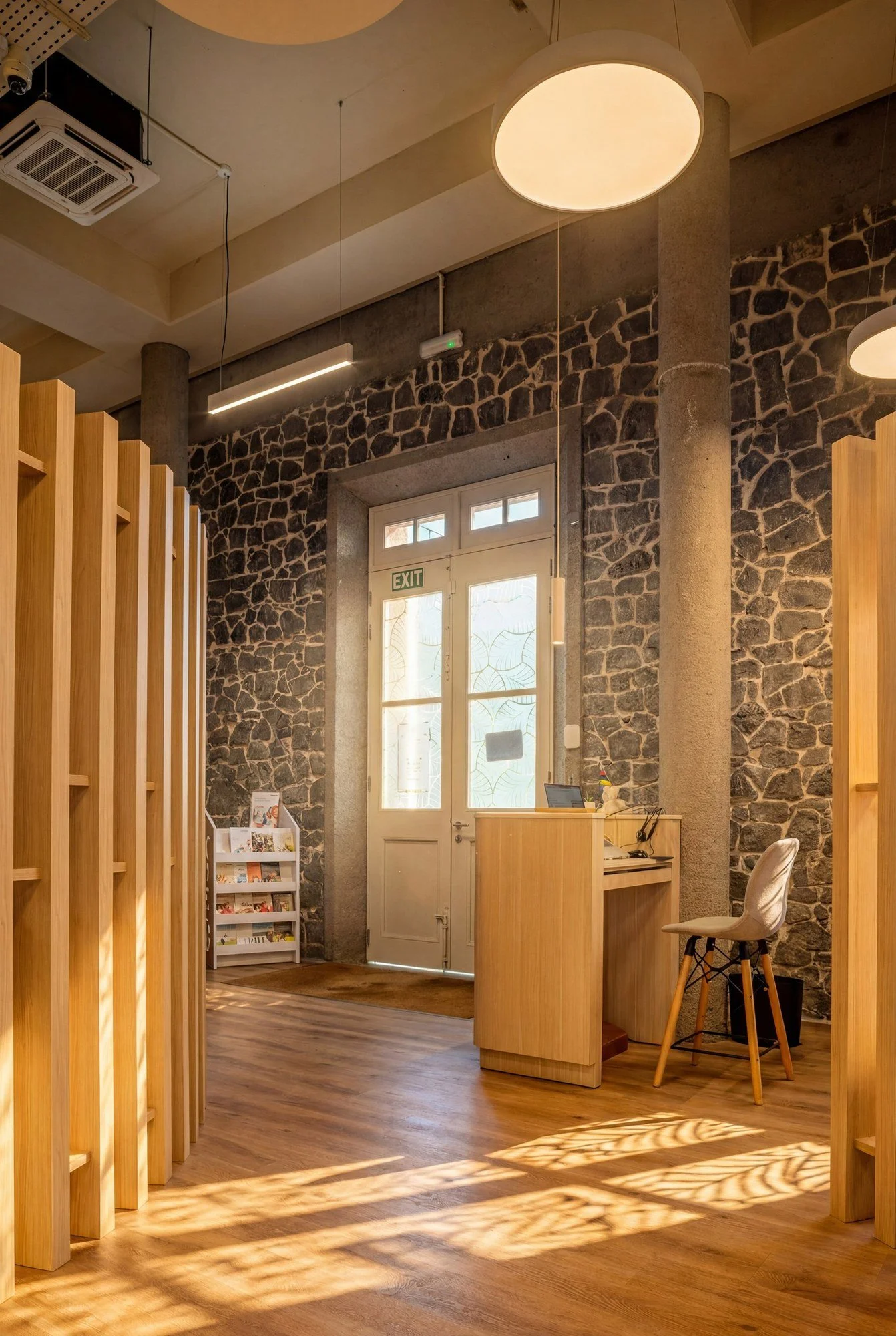 Accueil des bureaux MUA VUT intégré à un bâtiment historique en pierre volcanique.