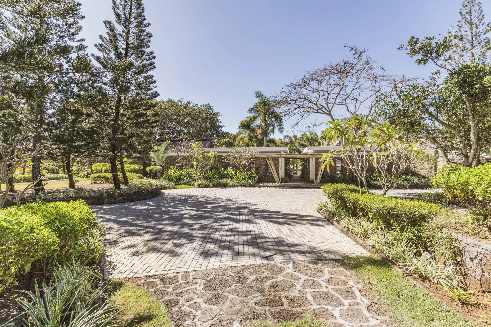 Landscaped entrance courtyard with timber pergola and mature trees