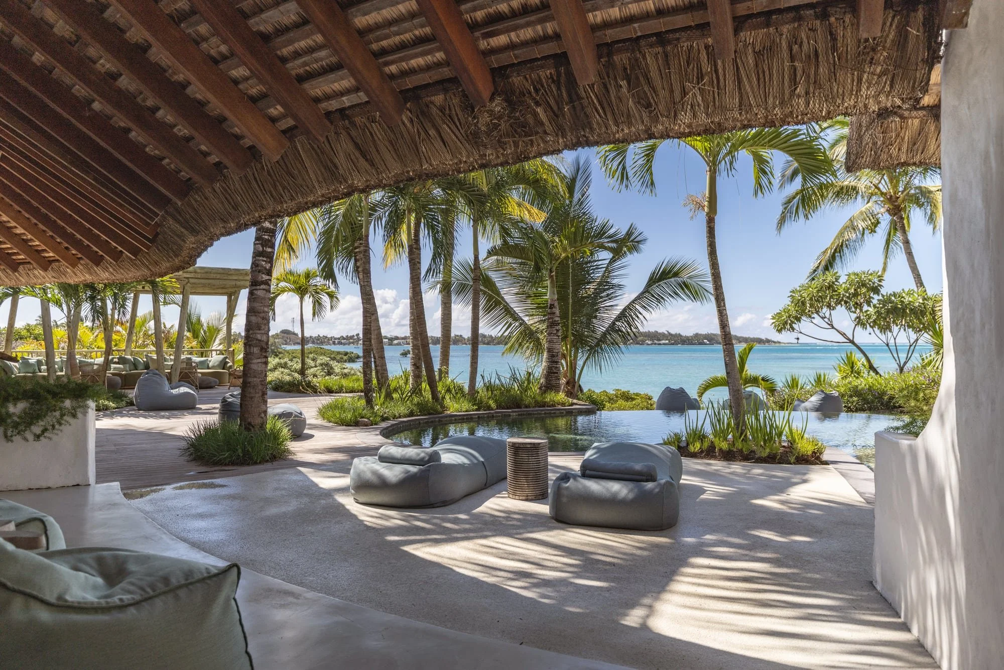 Pool lounge framed by palms with an expansive lagoon view
