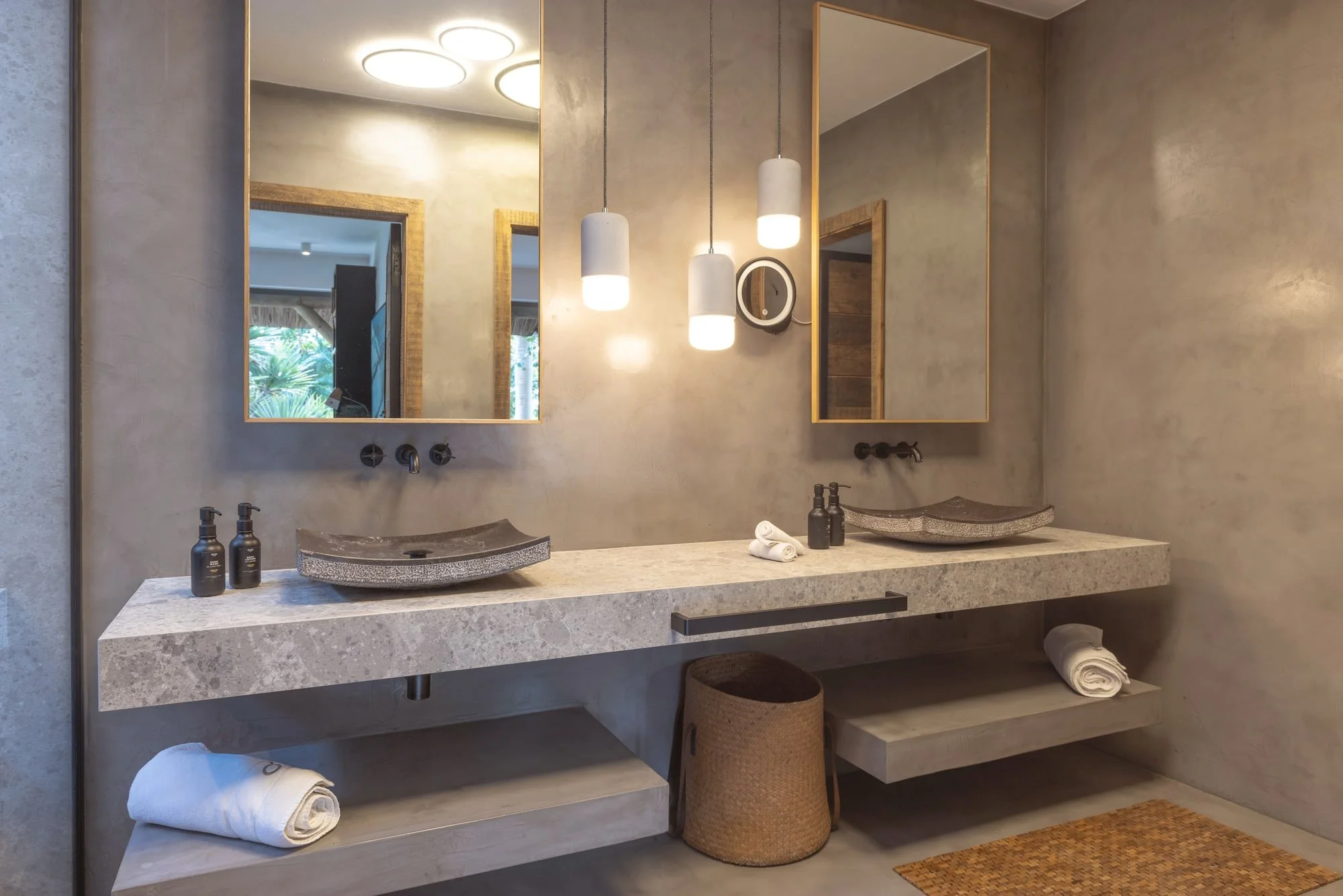 Minimal concrete bathroom with a stone double vanity and warm lighting